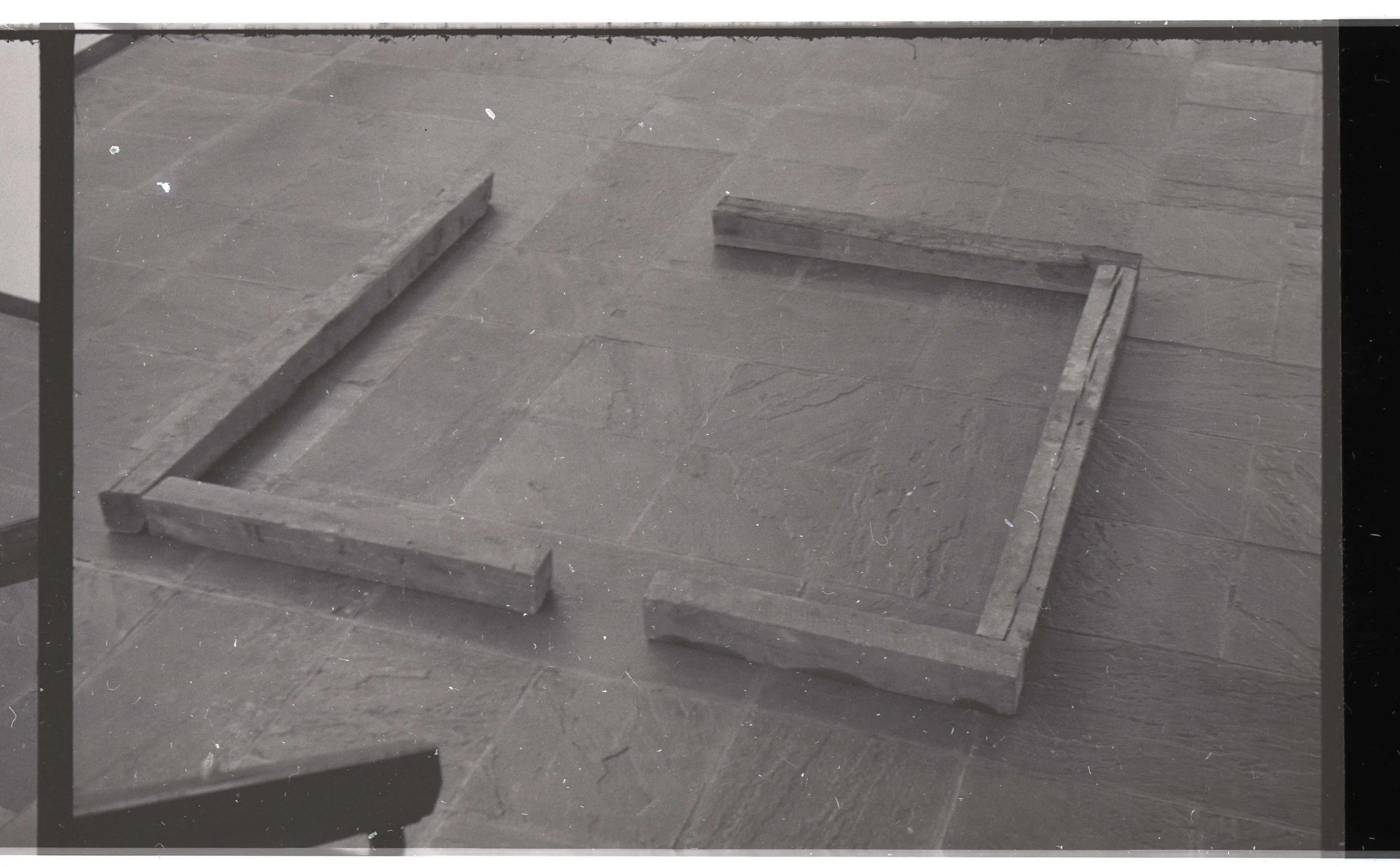 A partially assembled wooden frame on a stone or concrete floor.