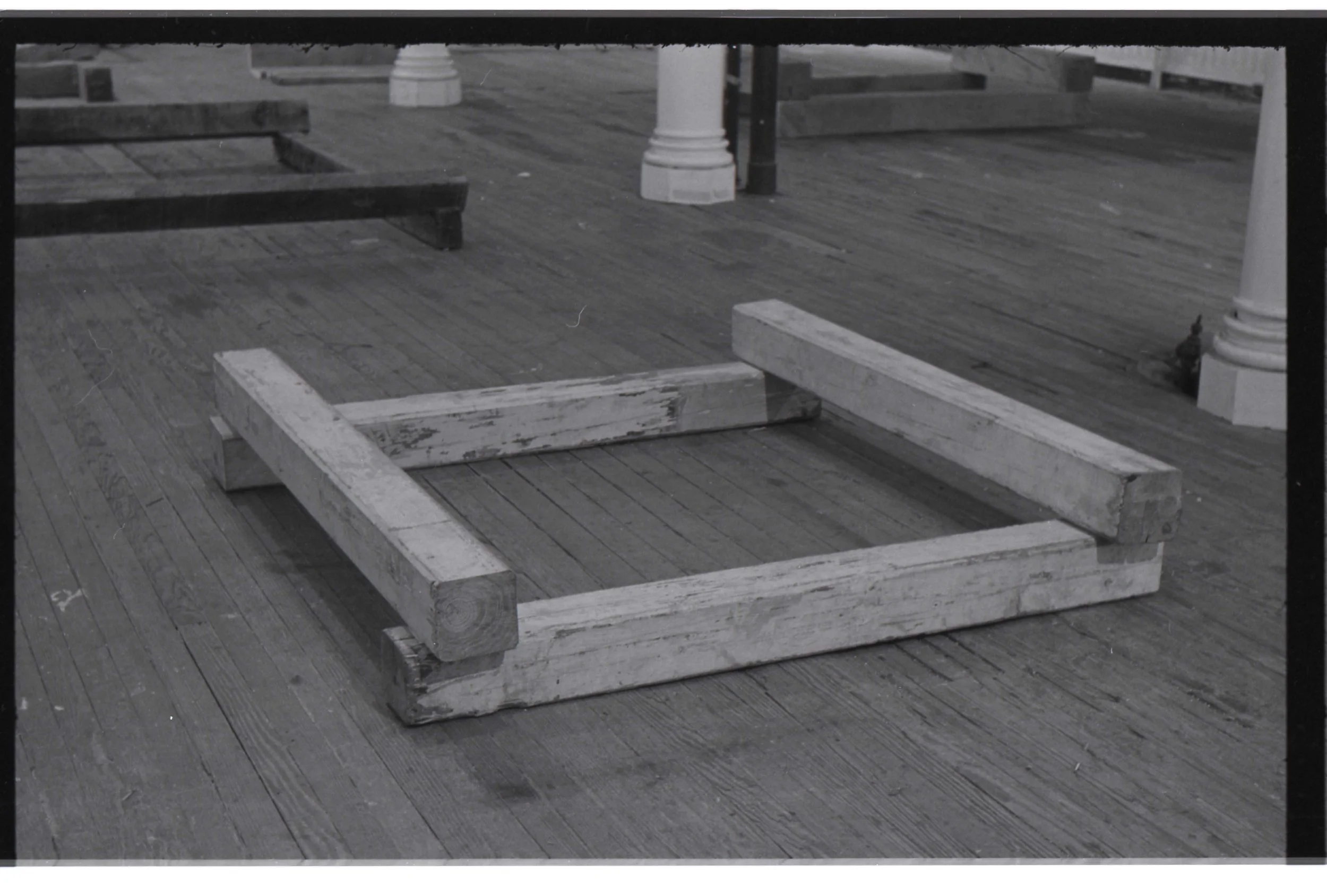 Disassembled white wooden bed frame on a wooden deck floor.