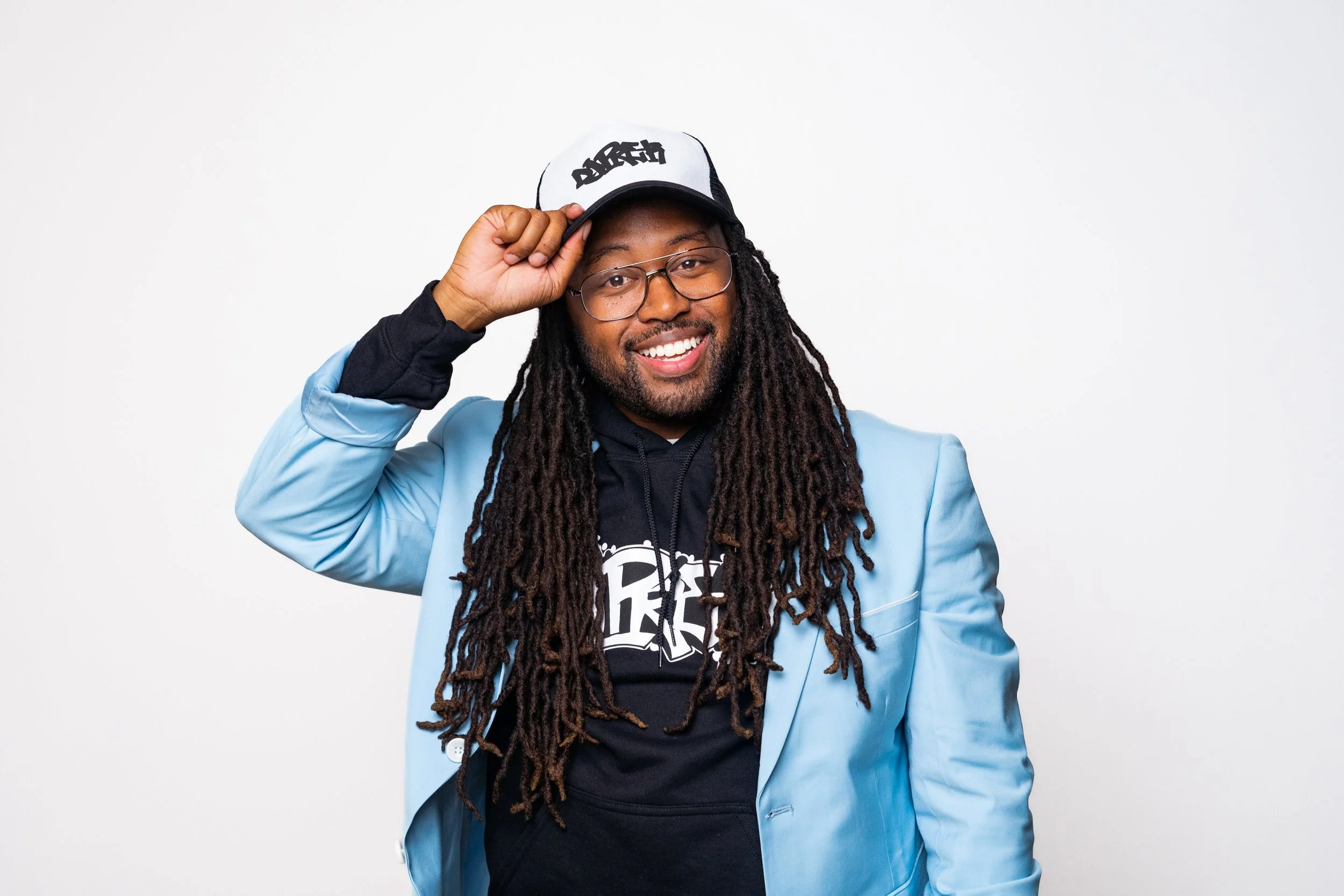 DJ Pre-K smiles while holding a DARE cap in a studio portrait.