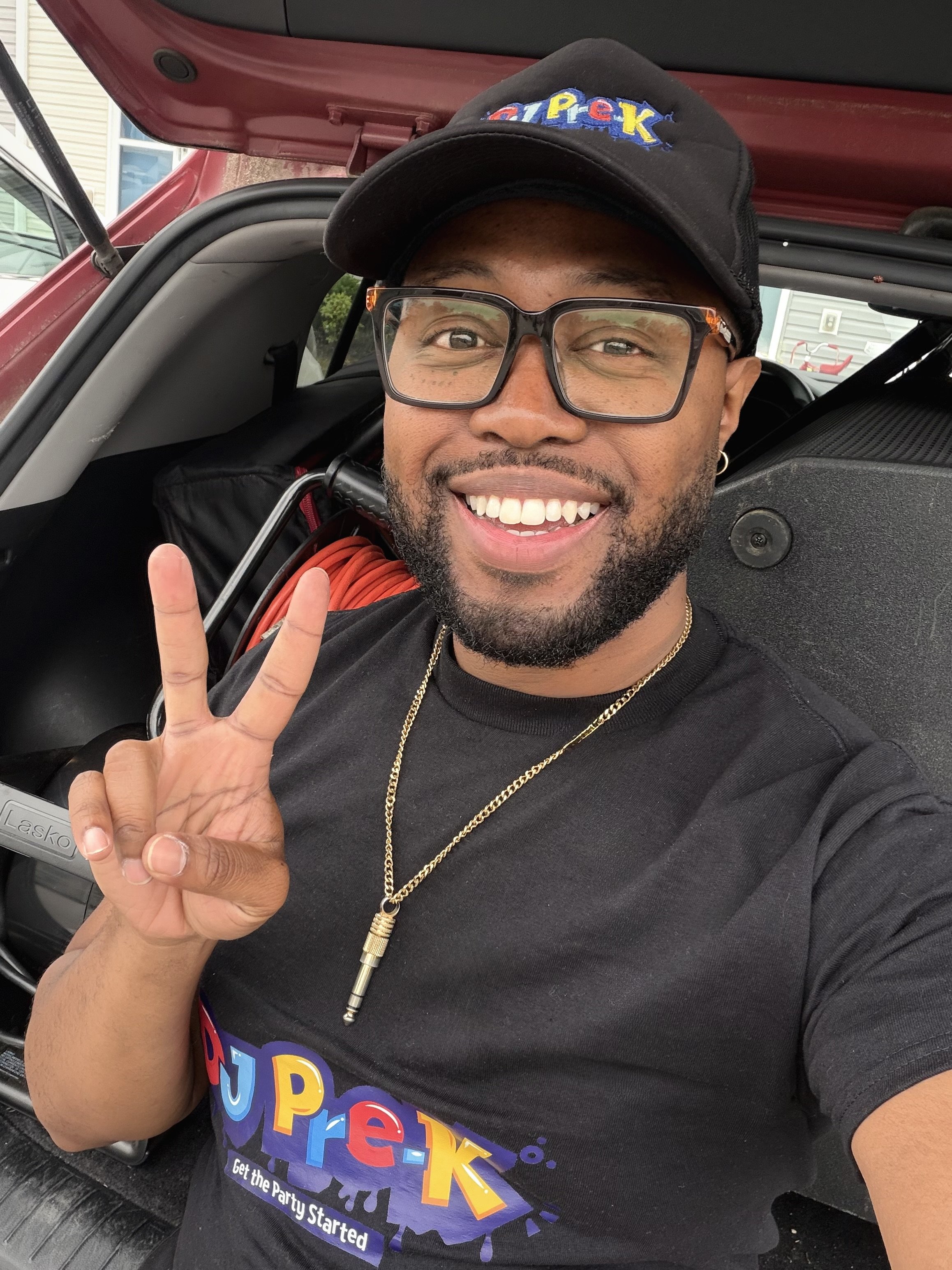 DJ Pre-K smiles and flashes a peace sign while preparing for an upcoming event.