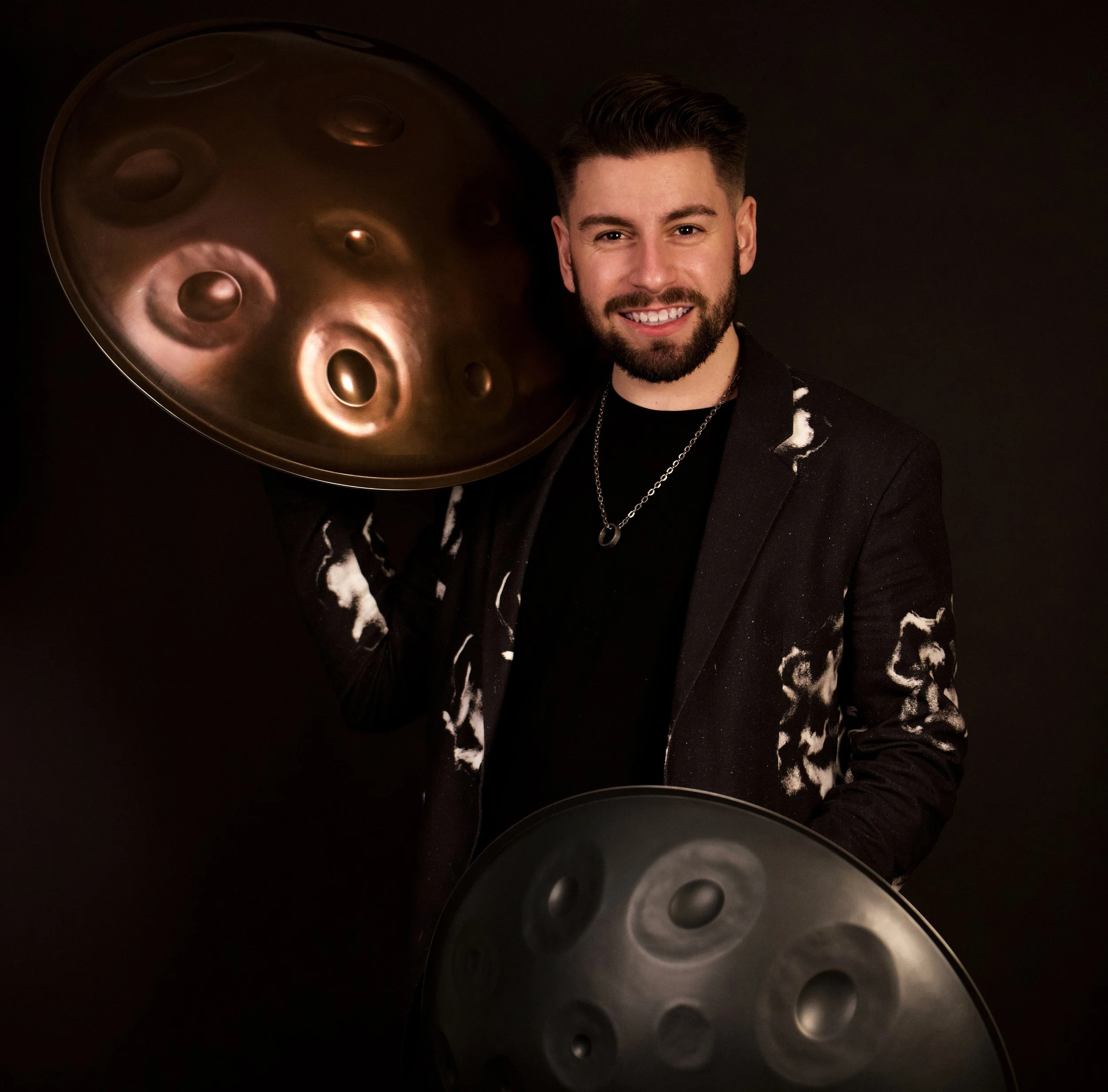 Close-up of a person smiling, holding a disc-shaped thunder mug, against a dark background.