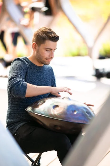 Young man playing a steelpan drum outdoors.