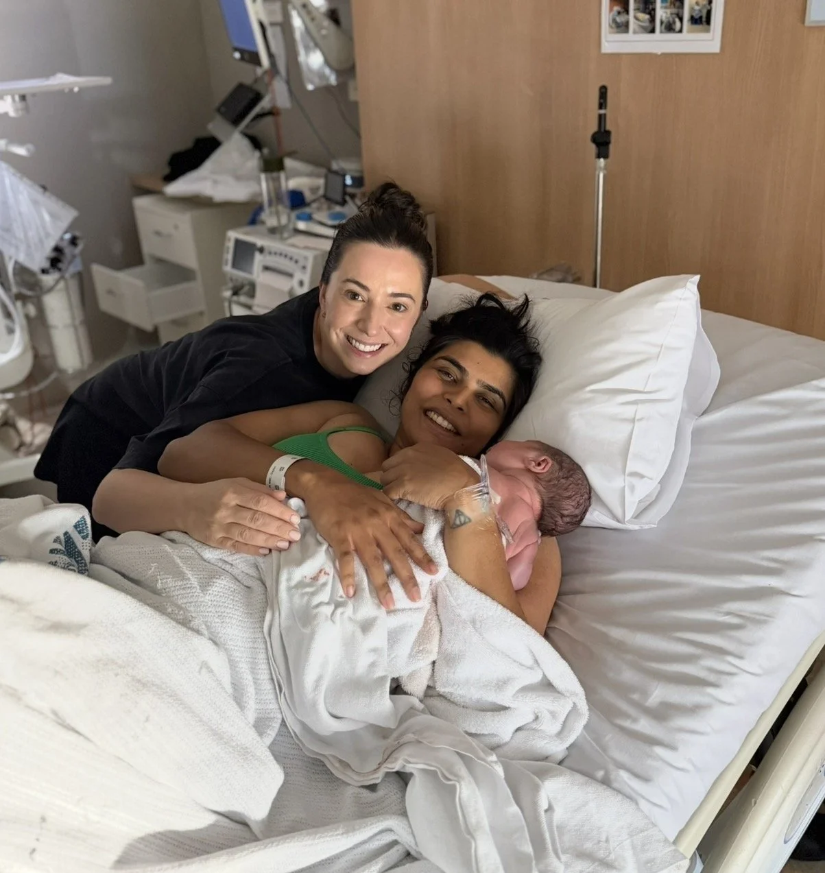 Steph the Doula hugging her vaginal birth client Sharon after the birth of her new baby, she is holding in her arms.