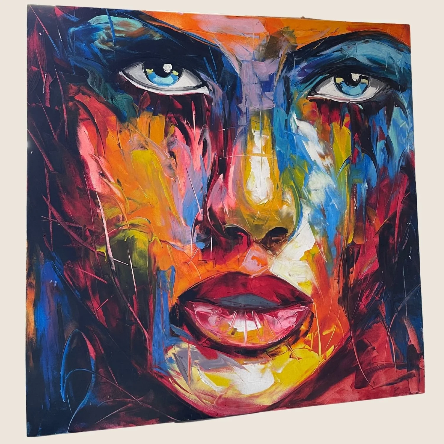 Large unframed oil painting of an expressive close-up female face in bold gestural brushstrokes of blue, orange, red and yellow, photographed in a busy framing studio