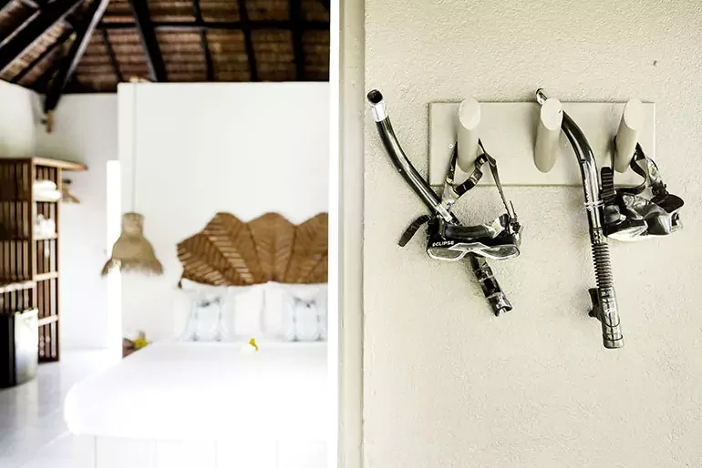 A wall-mounted hook with two bicycle helmets hanging in a room with a bed and wooden décor.