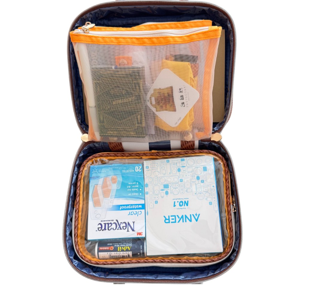 Open travel case containing a small package of a first aid kit, a sealed water purifier, and various travel documents and accessories for Touring Artists.
