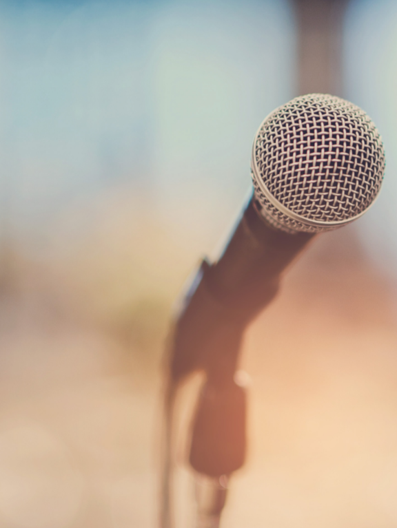 Close-up of a microphone on a stand, blurred background.