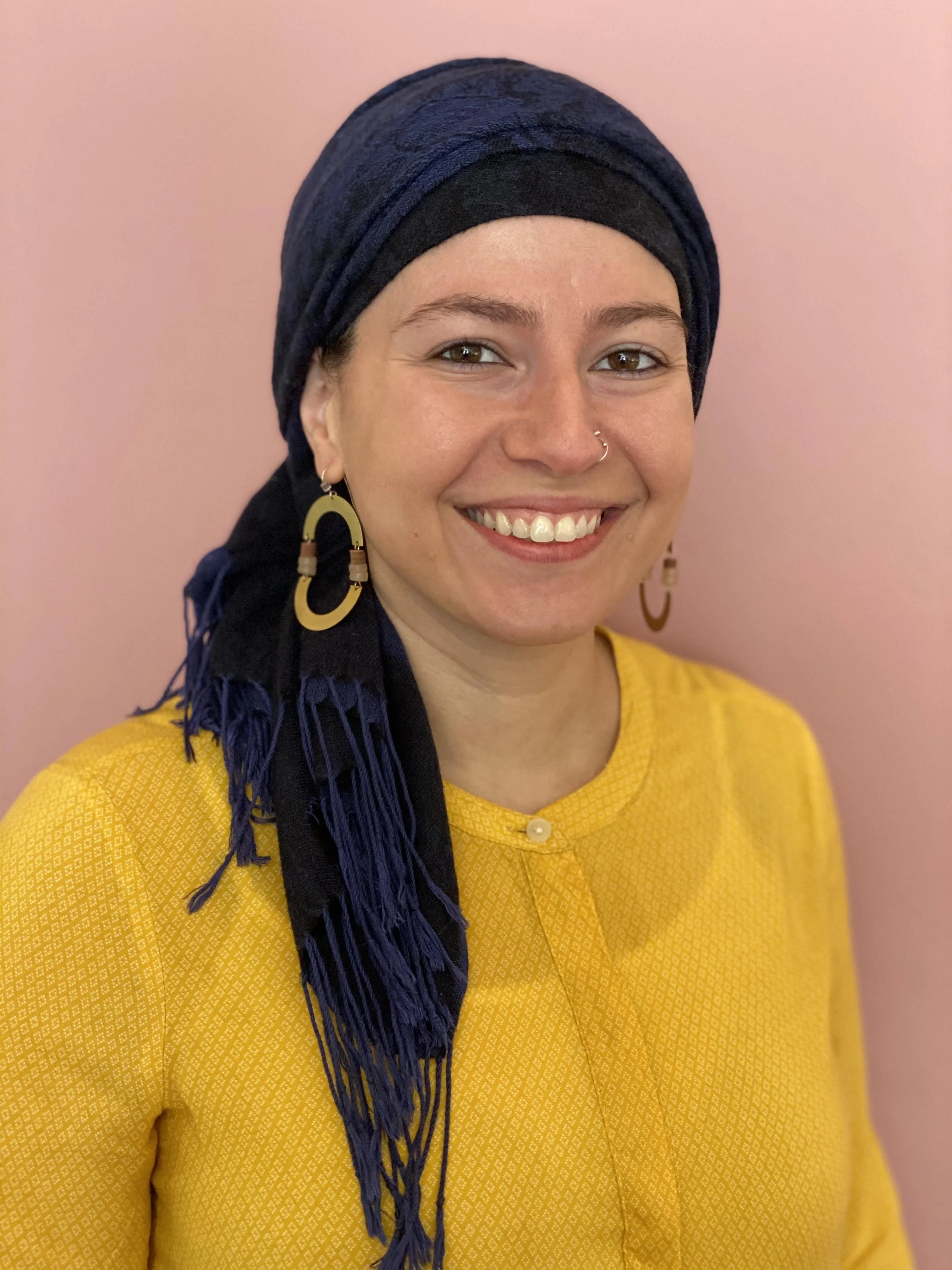 head shot of Sara Ghalaini, wearing a blue head scarf and yellow shirt. Light skin color.