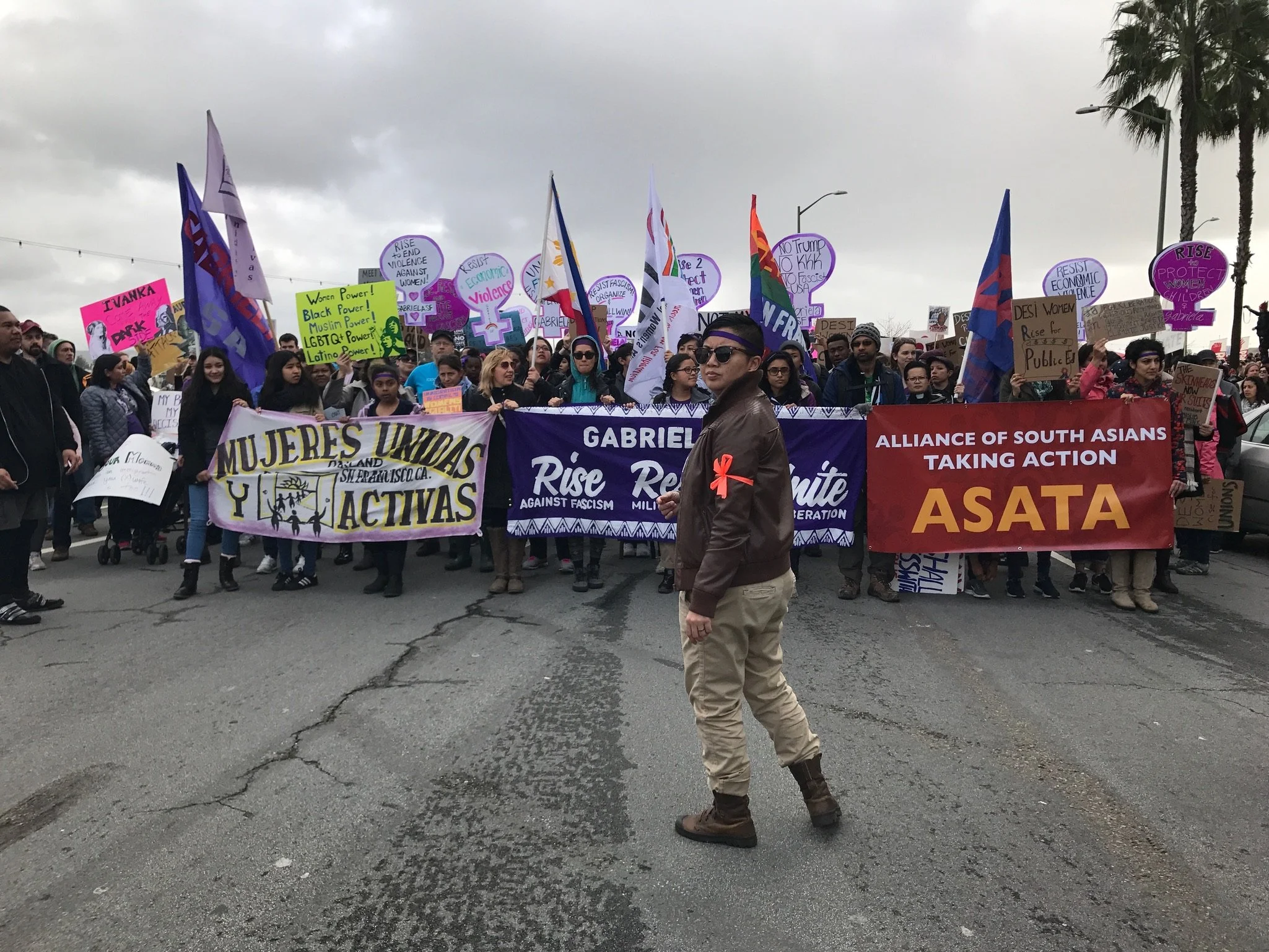 A group of people standing behind banners representing diverse communities at a march