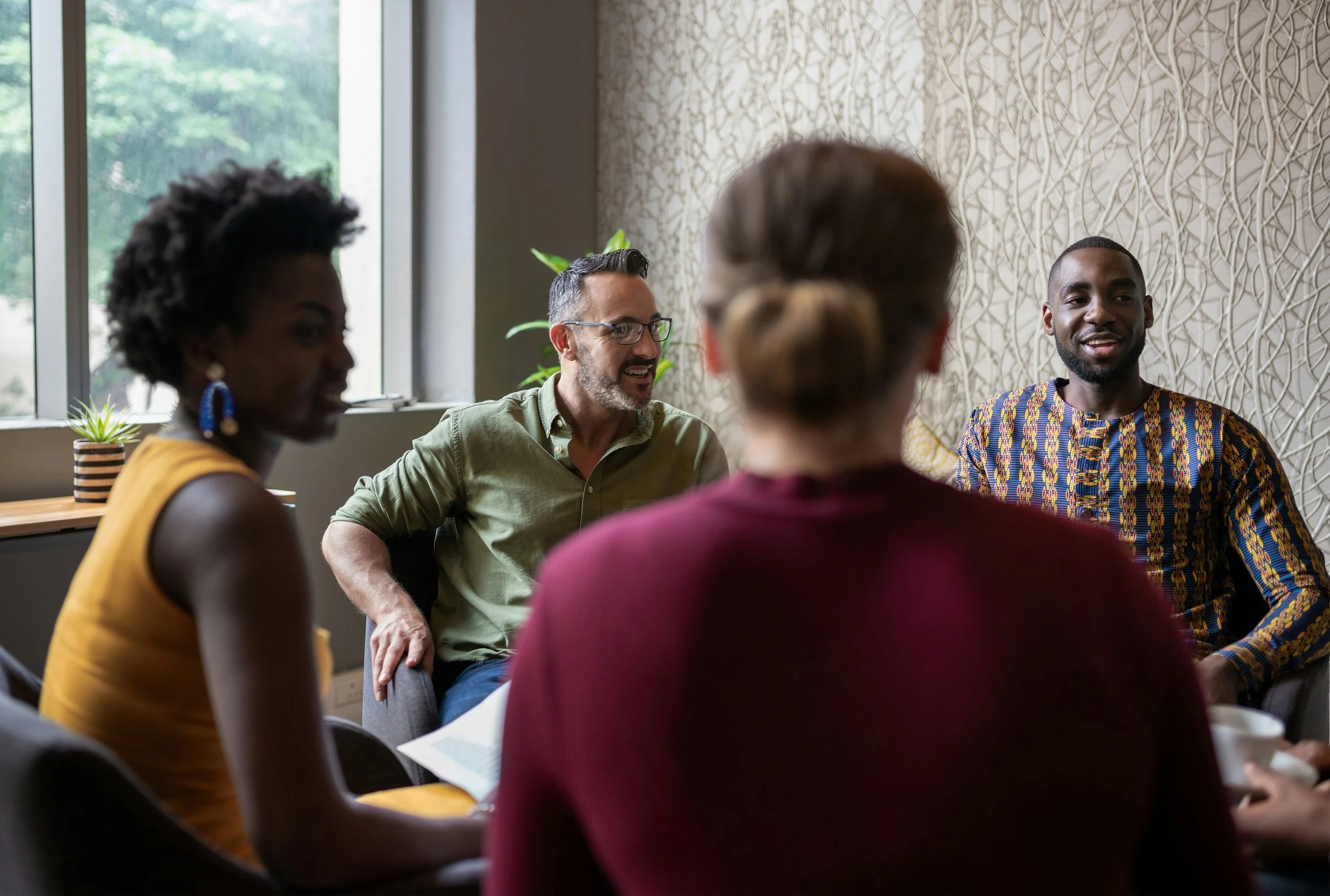 Group of racially diverse individuals sit facing each other.