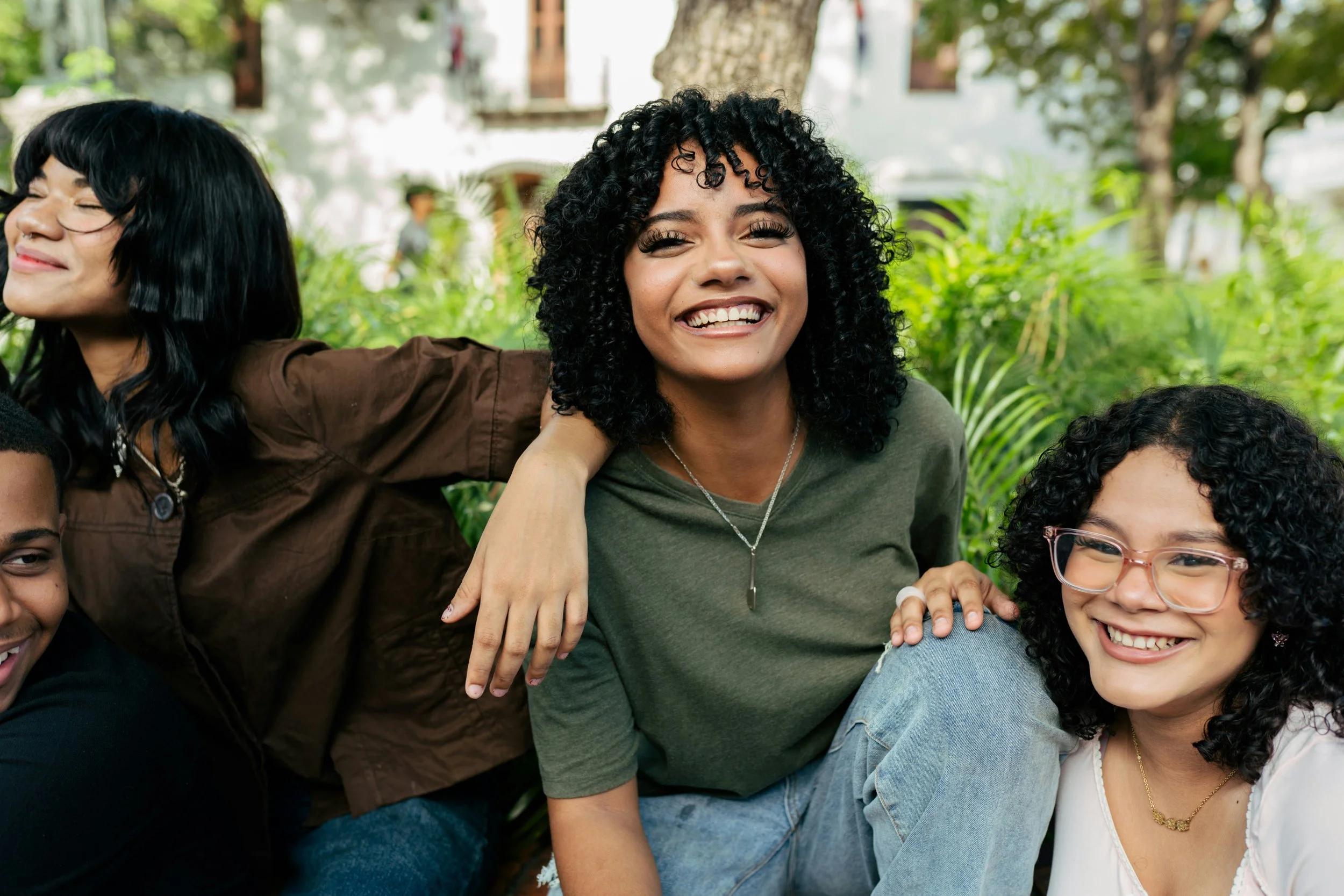 four brown skinned young adults with dark hair smiling with one looking at the camera