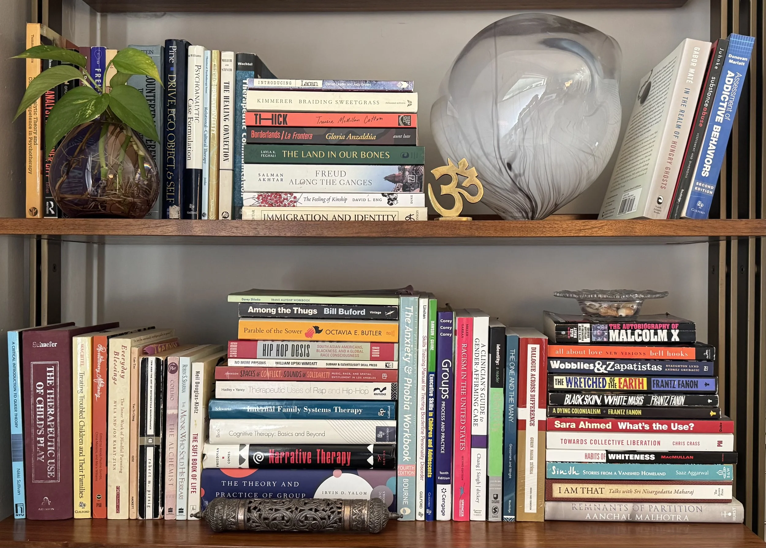 Two shelves with books stacked horizontally and vertically and various decorative objects