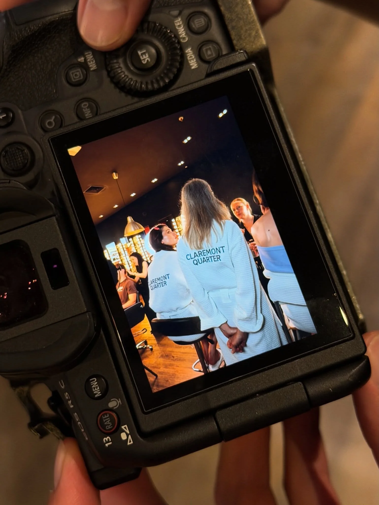 Photograph of a digital camera displaying an image of people in white uniforms in a restaurant or cafe setting.