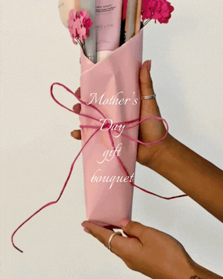 Someone holding a pink paper cone with pink carnations, with 