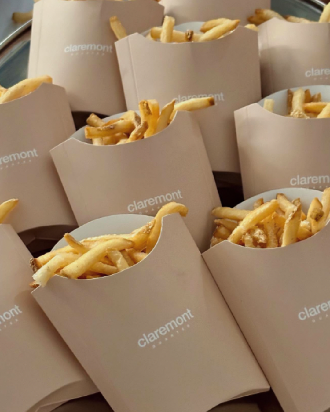 Multiple paper containers filled with French fries, branded with 'claremont'.
