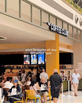 People dining and ordering at a coffee shop named 'The Coffee Club' inside a mall.