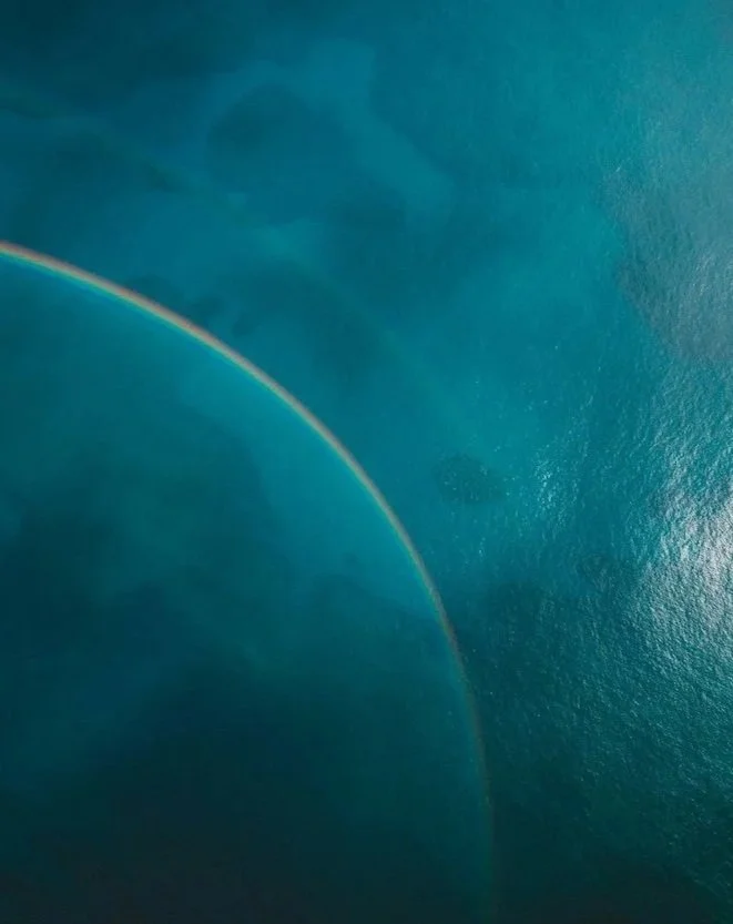 A rainbow arching over a large body of water.