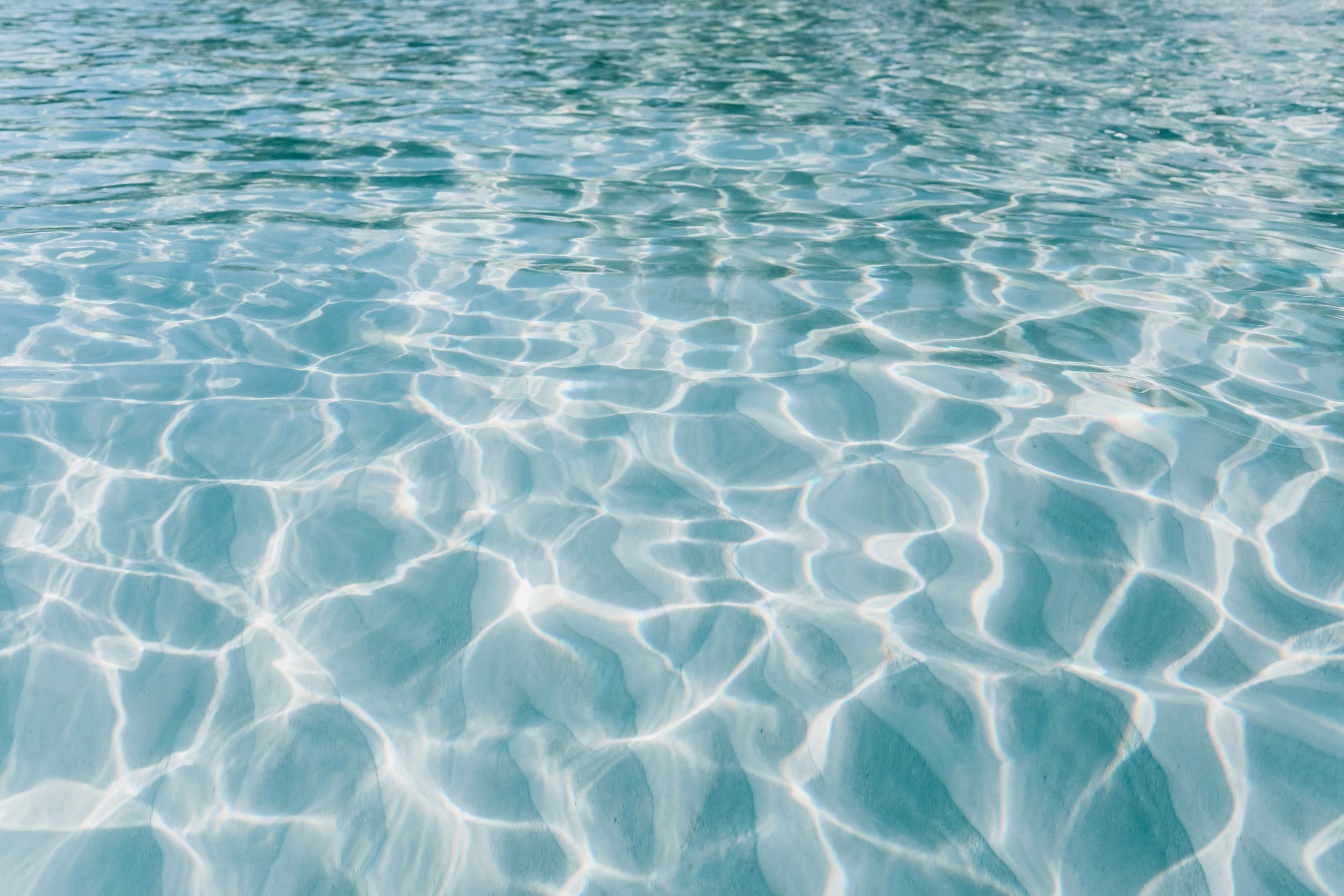 Clear blue water with sunlight reflections creating a rippling pattern.
