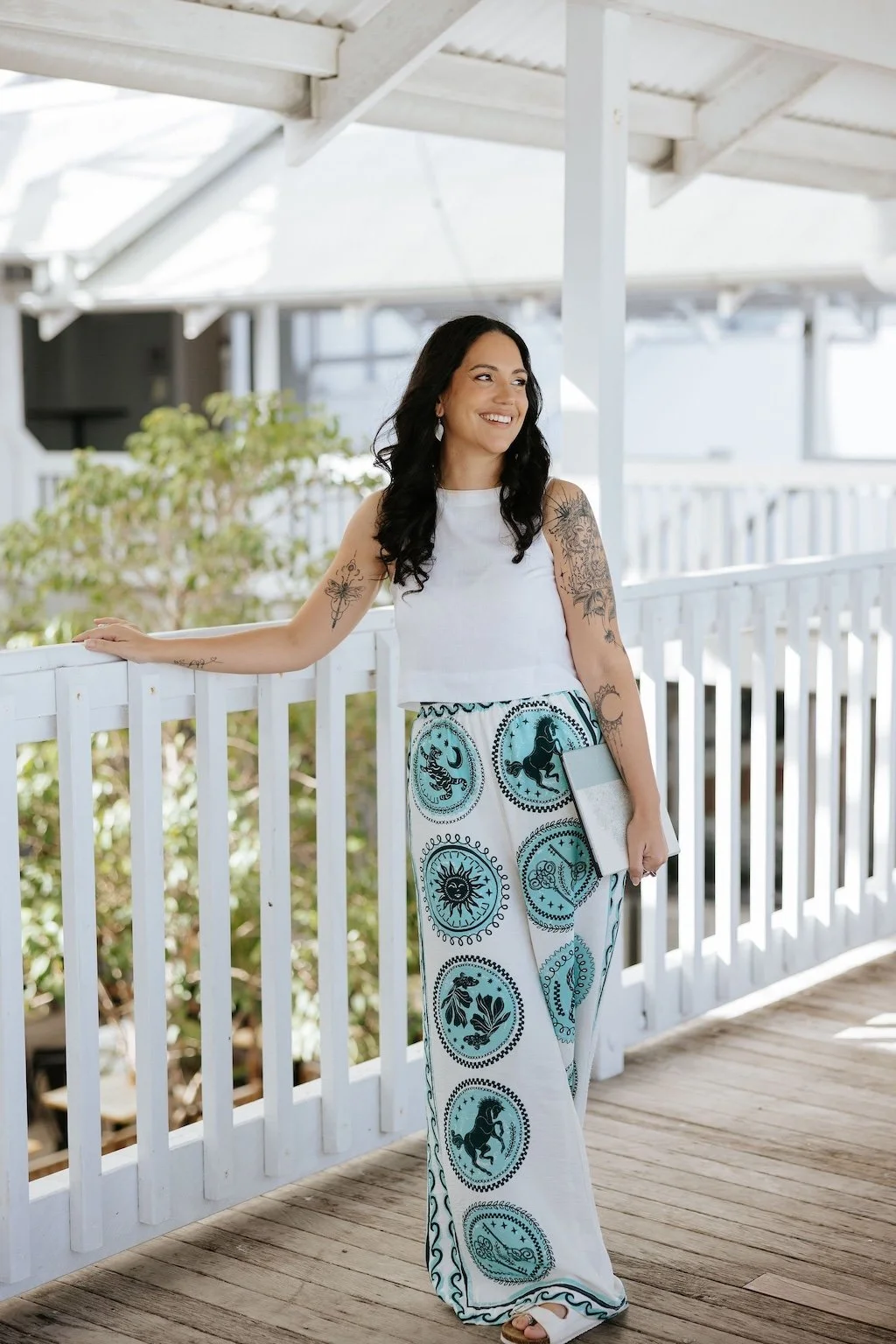 Candice Heffernan smiling while leaning on a white railing on a porch or balcony during daytime.