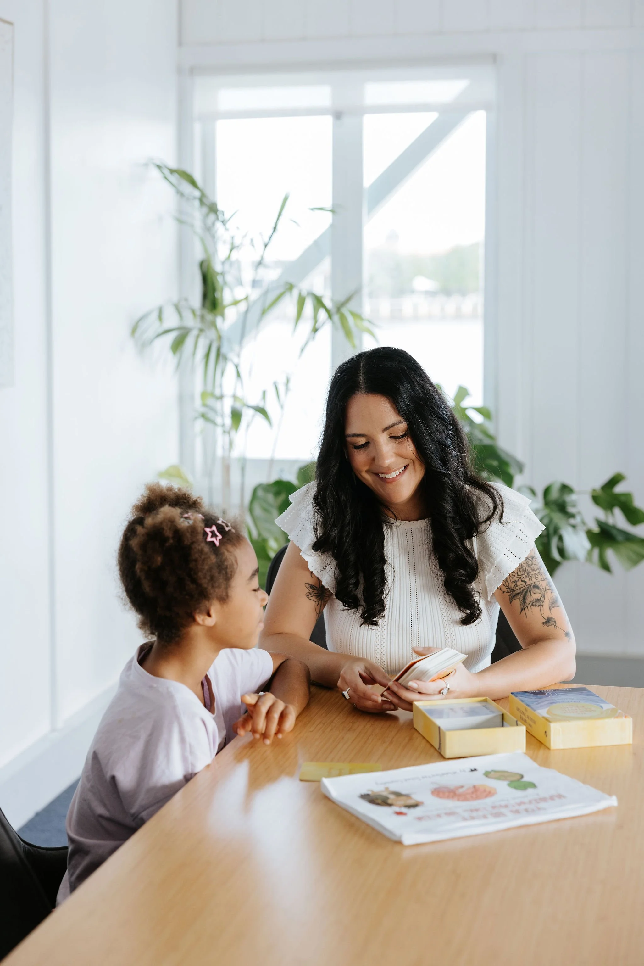 Candice Heffernan and a girl sitting at a table, working with cards to learn about personal strength.