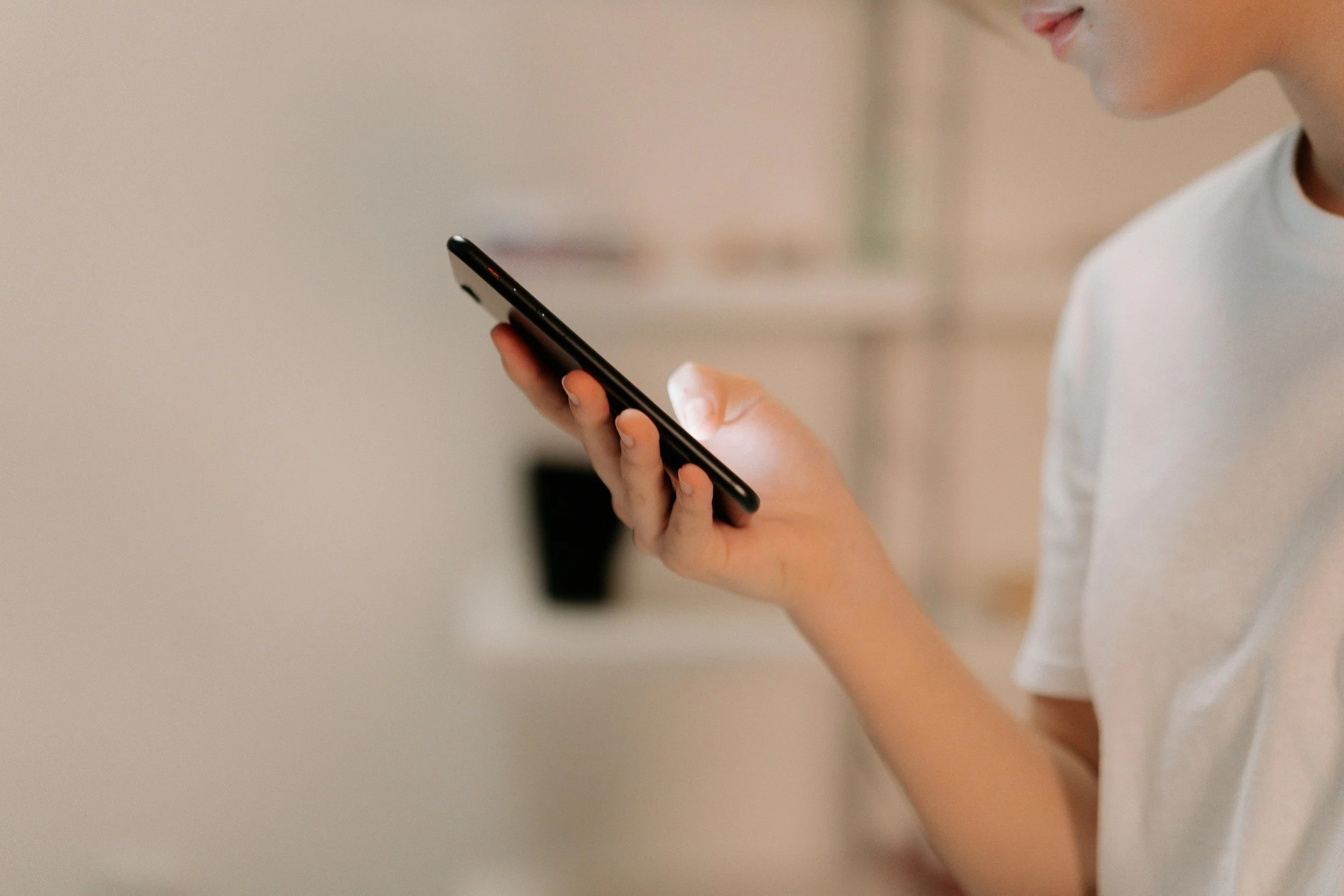 Close-up of a person with light skin looking at a smartphone, with their tongue slightly sticking out.
