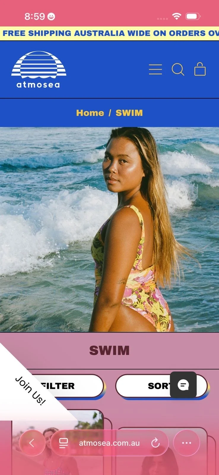 A woman standing in ocean waves during daytime, wearing a floral swimsuit, with a website banner for atmosa.com.au at the top of the image.