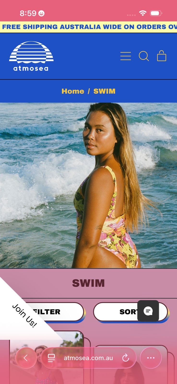 Screenshot of a website on a mobile phone featuring a woman in a yellow and pink swimsuit at the beach, with waves in the background, showing navigation options for shopping atmoSea souvenirs and swimwear.