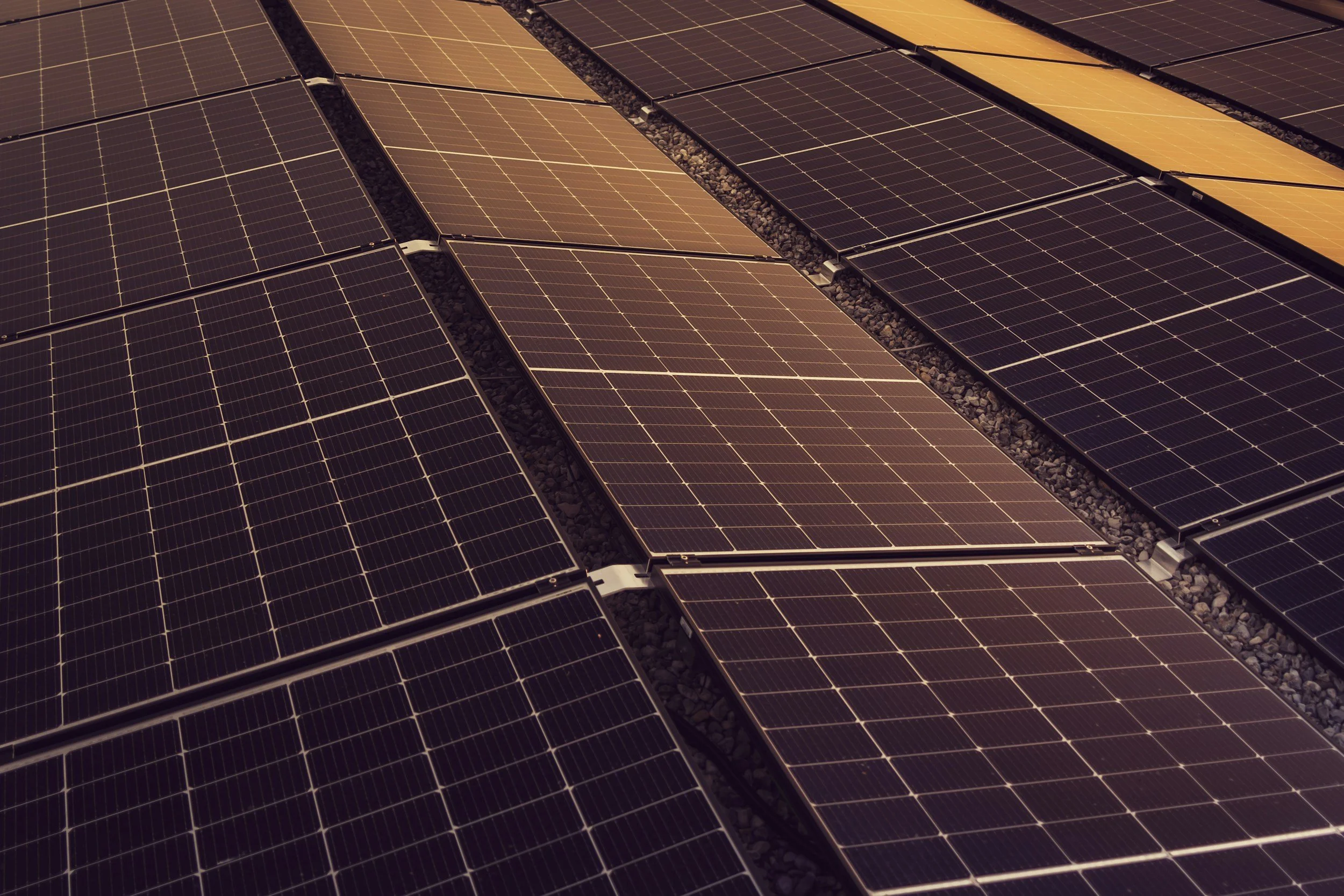 Aerial view of a ground-mounted solar array and warehouse complex, showing professional integration of renewable energy into a commercial landscape with high-definition clarity.