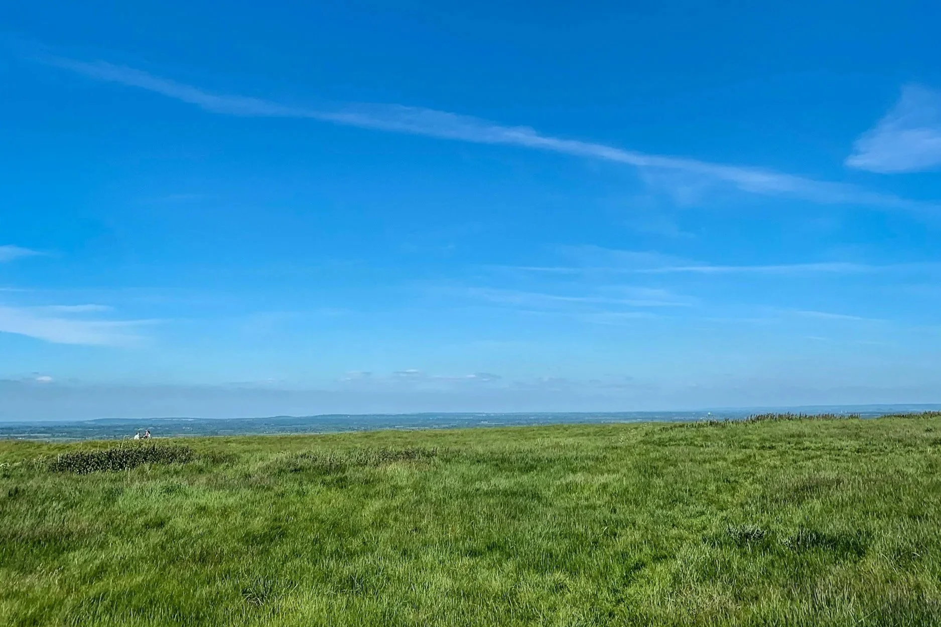A vast, open green field under an expansive blue sky. This represents a prime opportunity for solar panel or battery storage installations that generate steady monthly income.