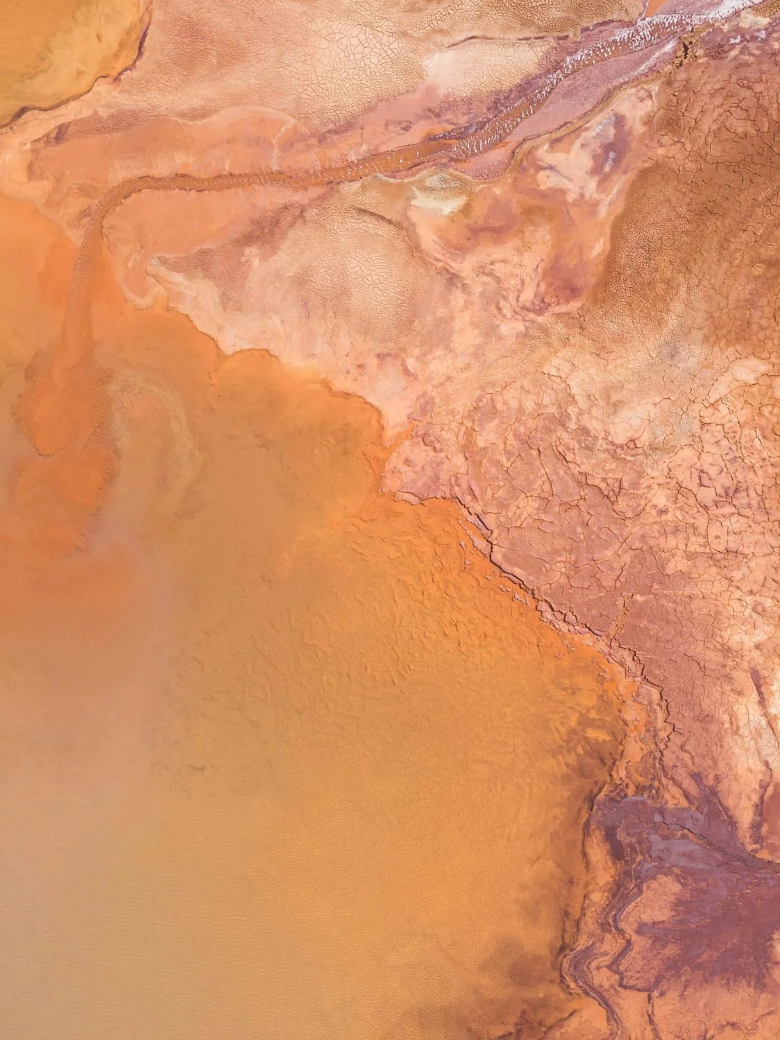 Luftaufnahme eines Terrakotta-Salzsees mit abstrakten organischen Mustern.