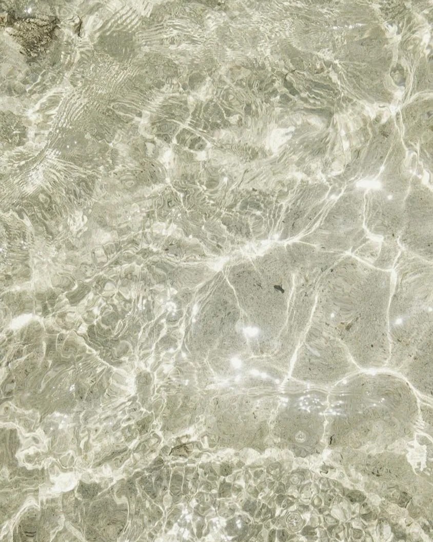 Klares flaches Wasser auf sandigen Strand mit sanften Wellenmuster.