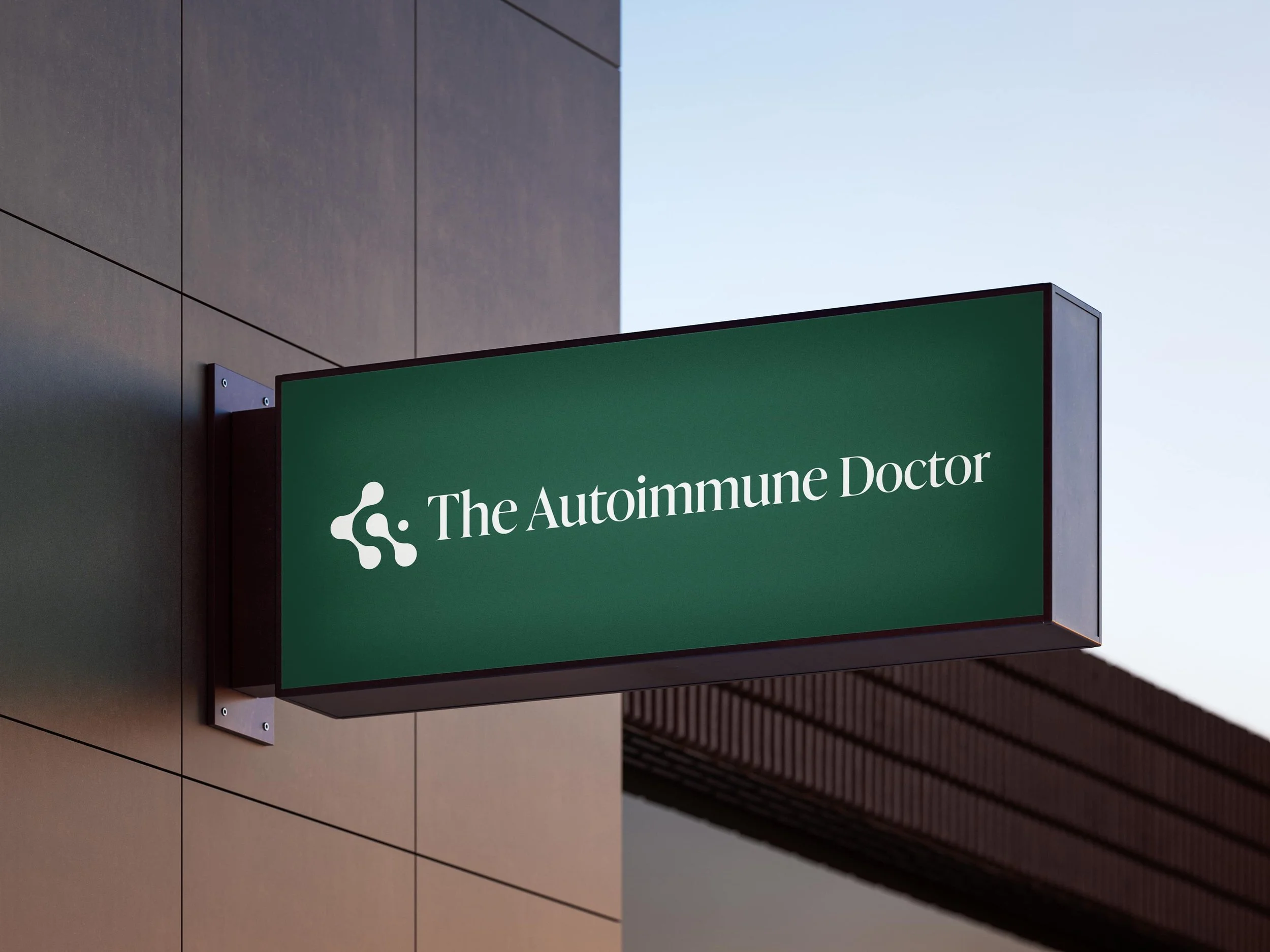 Exterior of a modern building with a green sign that reads 'The Autoimmune Doctor' mounted on the wall.