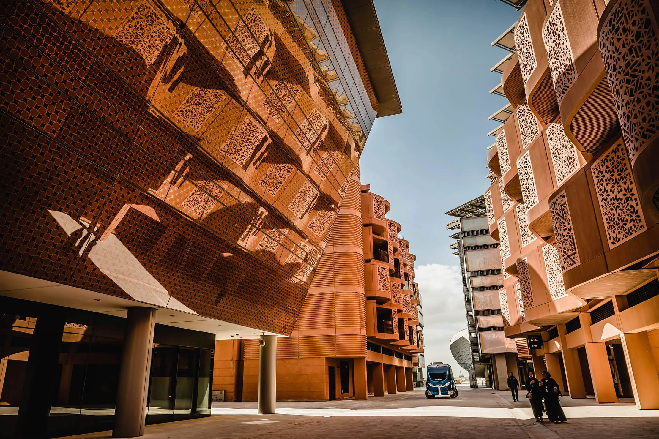 Pedestrians and an autonomous vehicle among the shaded streets of Masdar City, Abu Dhabi.