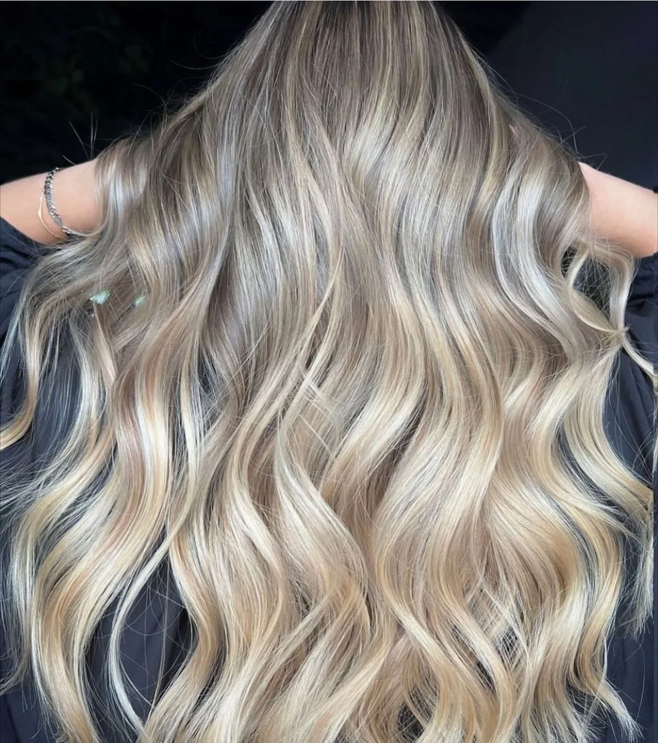 Long, wavy blonde hair with highlights, styled in loose curls.