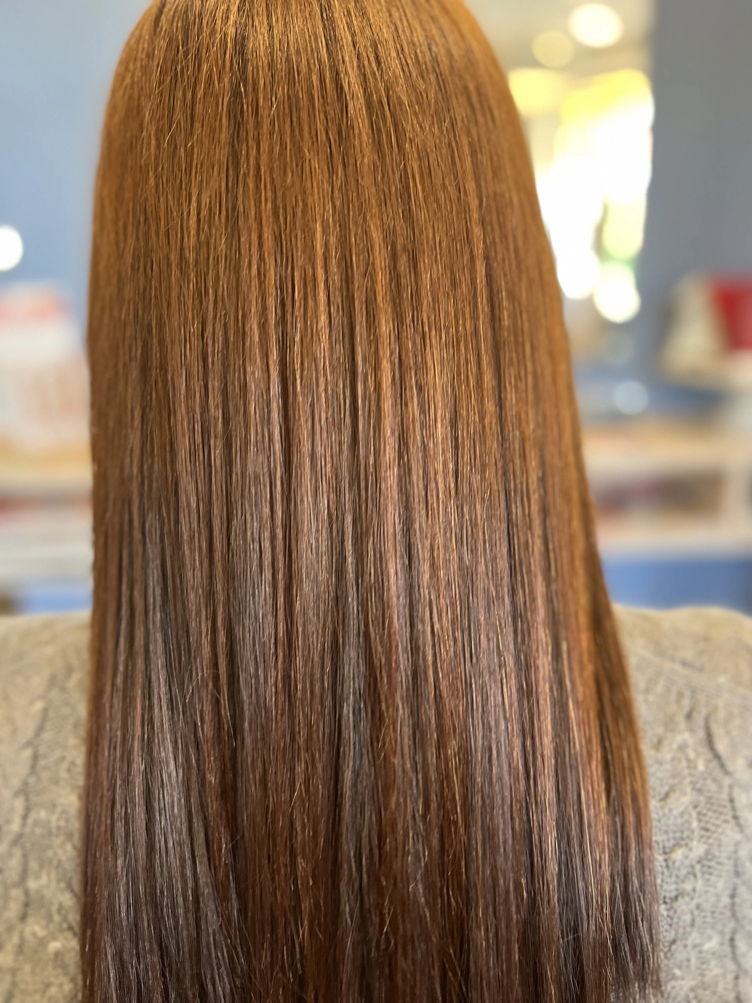 Close-up of straight, shiny, reddish-brown hair strands.
