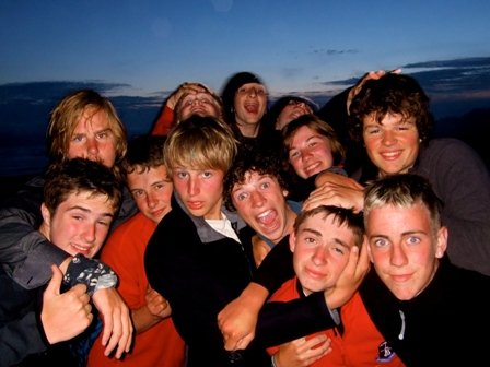 Group of teenagers smiling and hugging outdoors during sunset