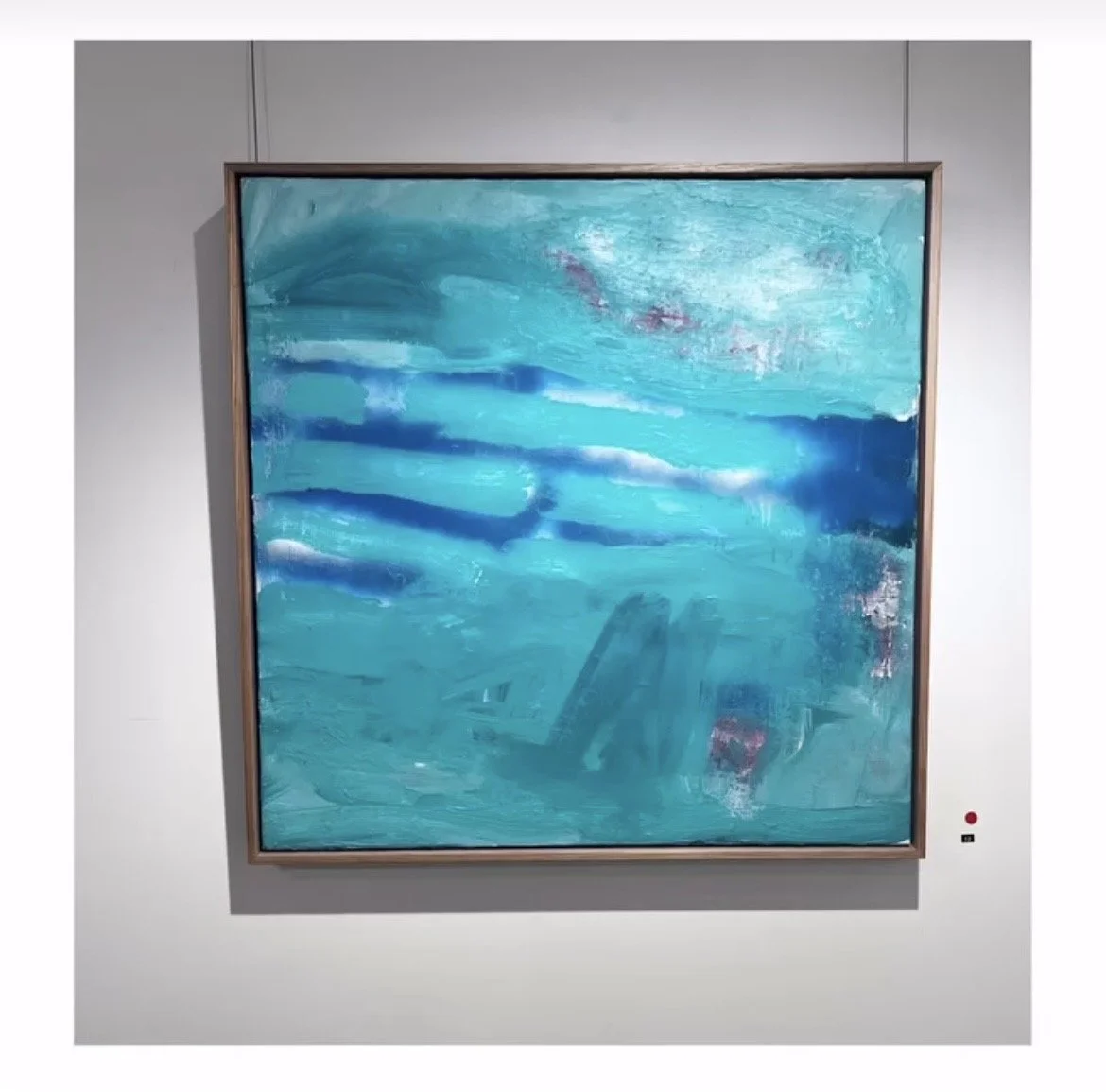 Abstract painting with shades of blue and hints of purple, framed and hanging on a white gallery wall.