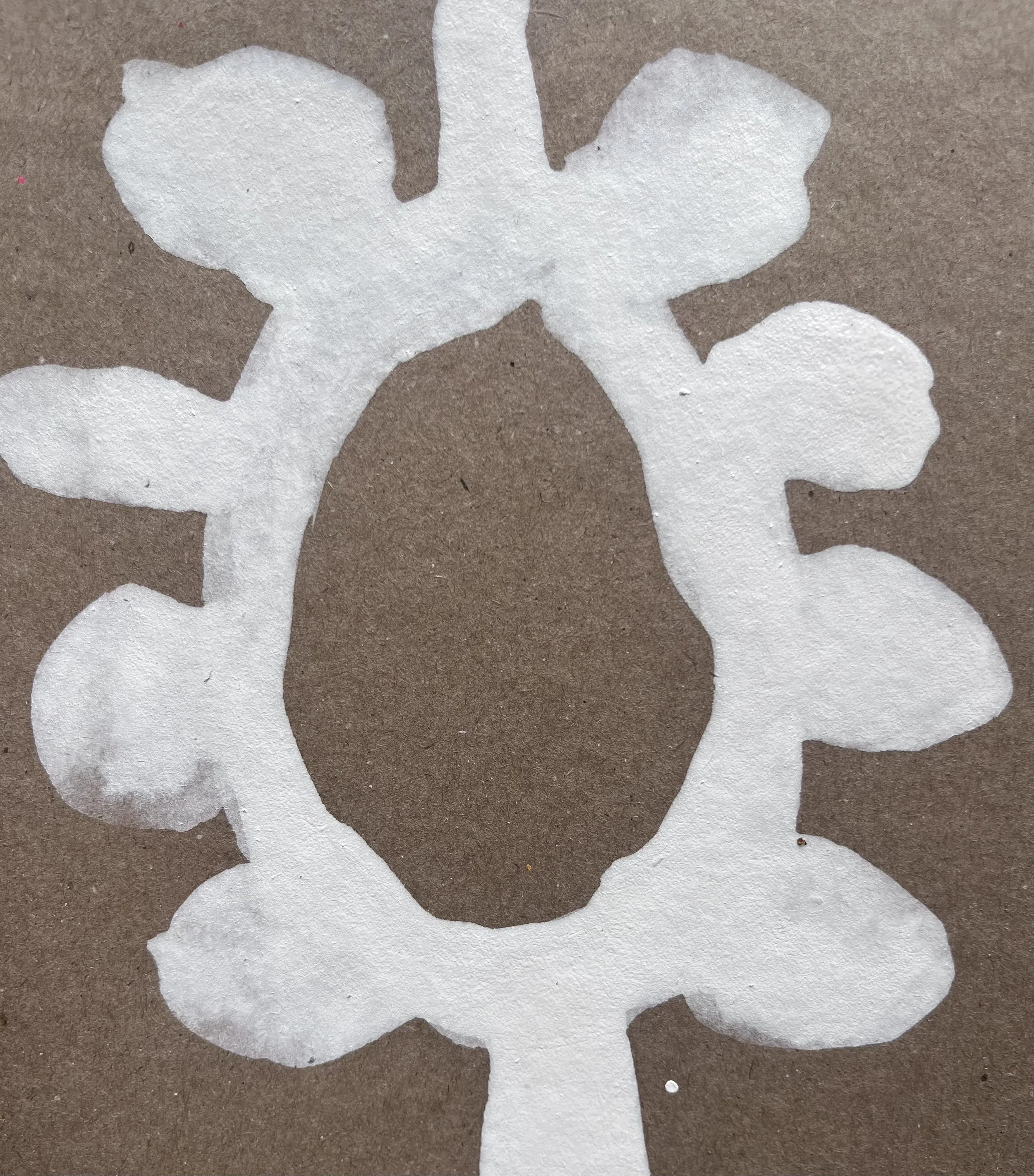 Close-up image of a white cut-out paper flower on a brown background.
