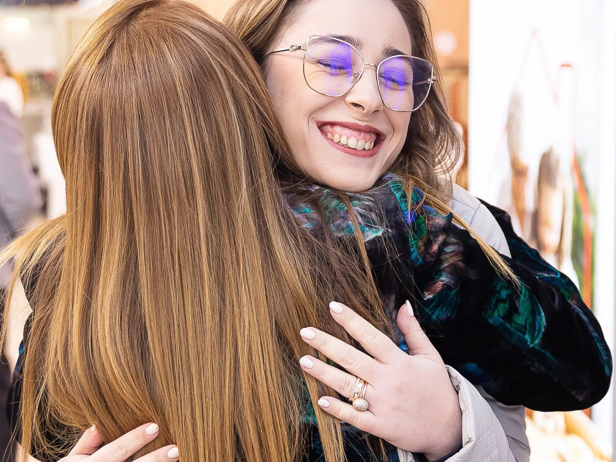 Two women hugging, with one woman smiling and wearing glasses.