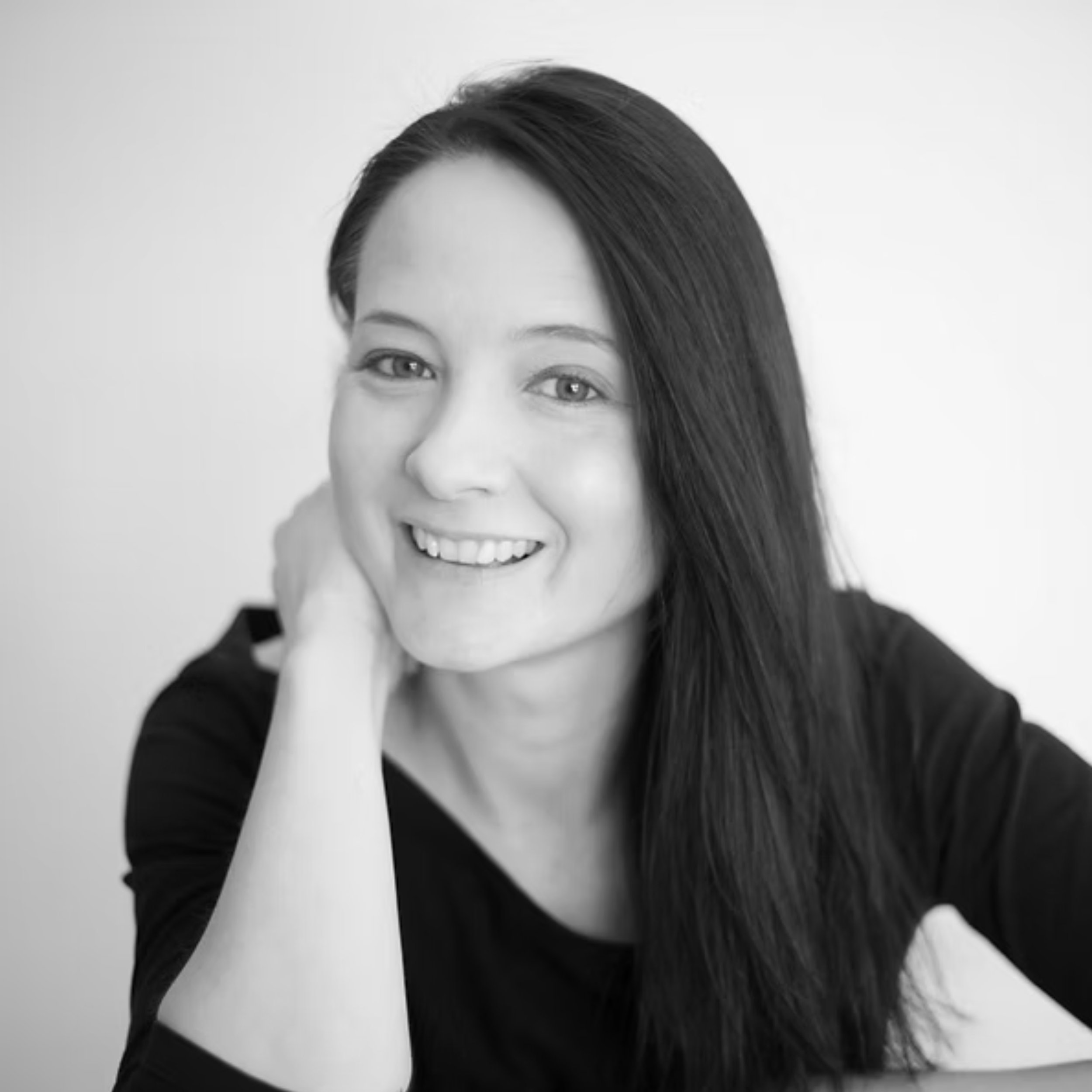 Close-up of a woman with long dark hair smiling, in black and white.
