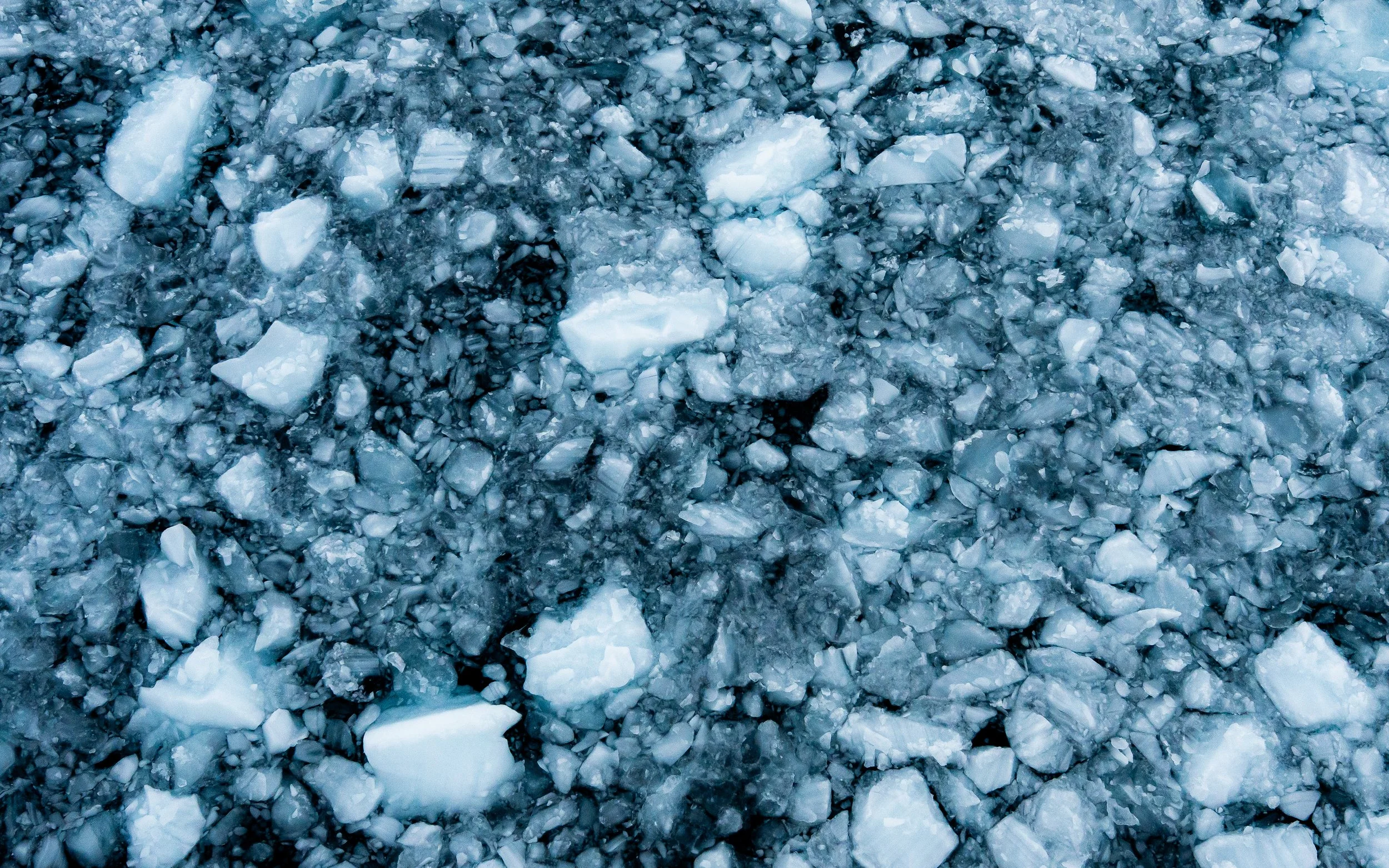 Close-up of a glacier with ice chunks and fractured ice in shades of white, blue, and gray.