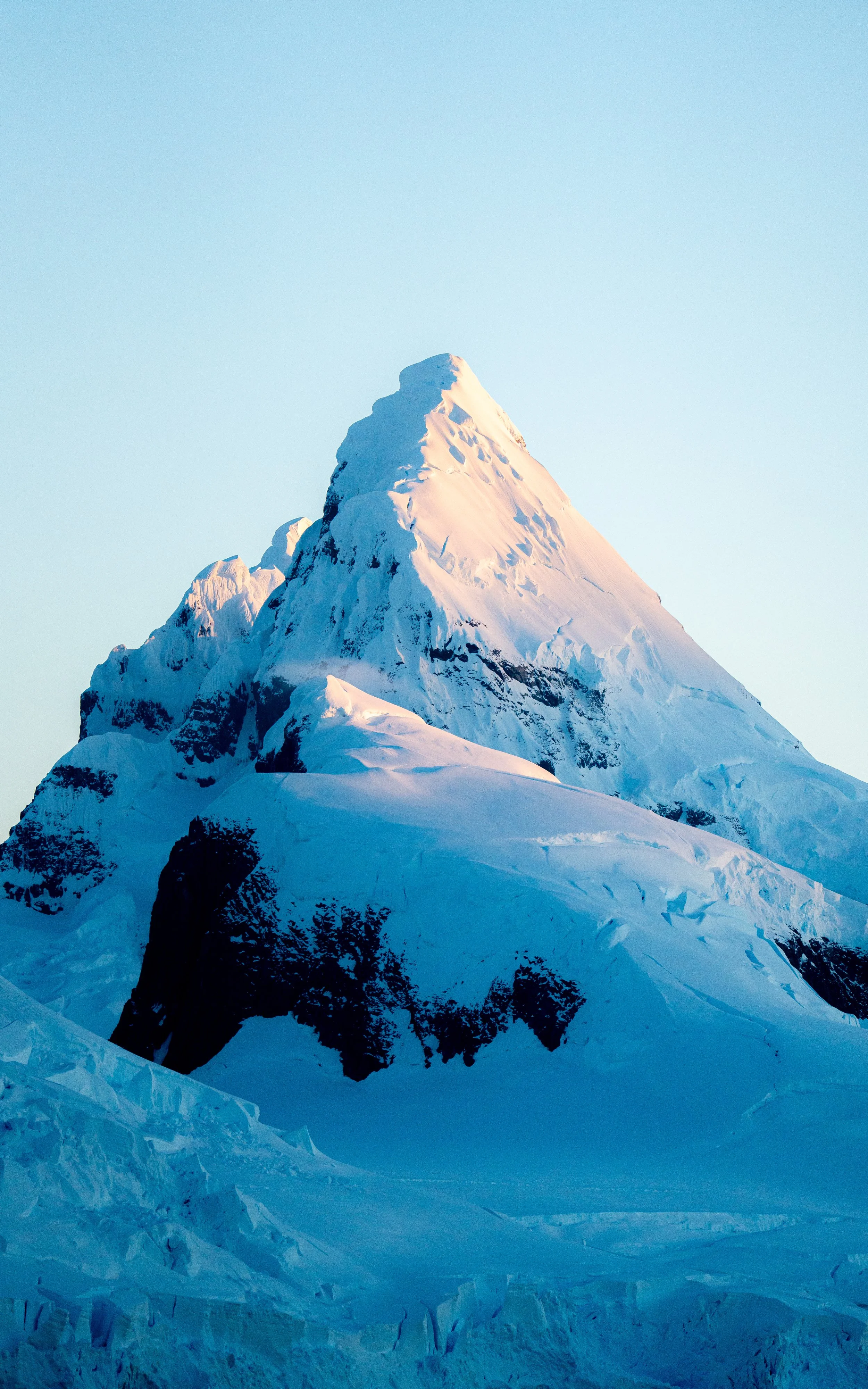 Snow-covered mountain peak against a clear blue sky.