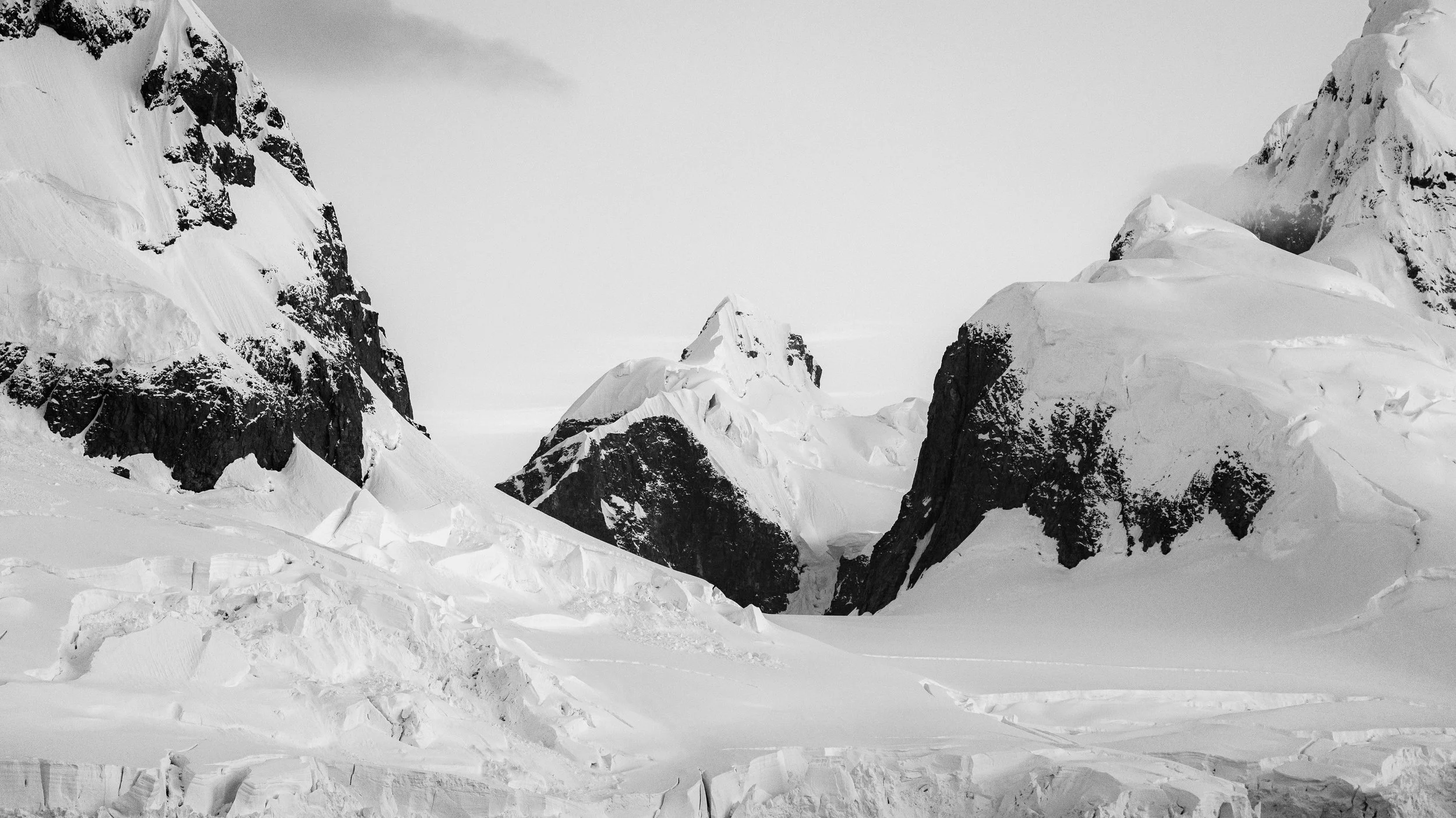 Black and white photograph of snow-covered mountain peaks and ridges.