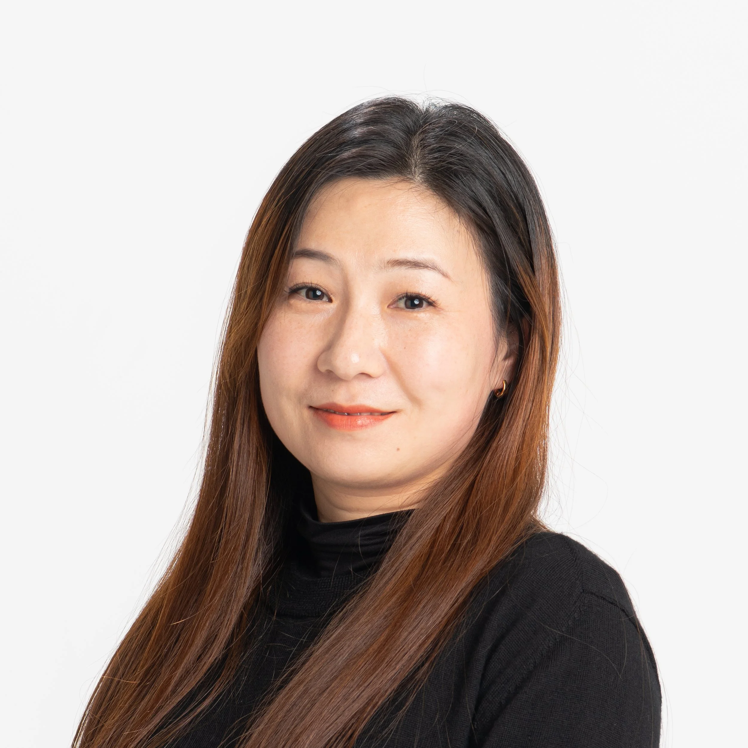 Close-up of an Asian woman's face with long, straight brown hair, smiling, wearing a black top, against a plain white background.