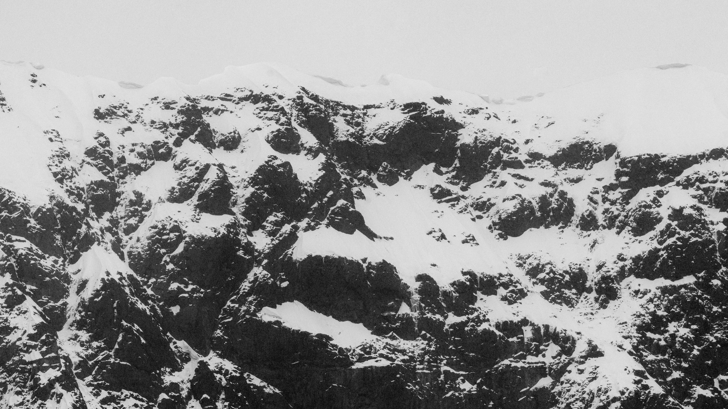 Snow-covered mountain with dark rocky peaks.