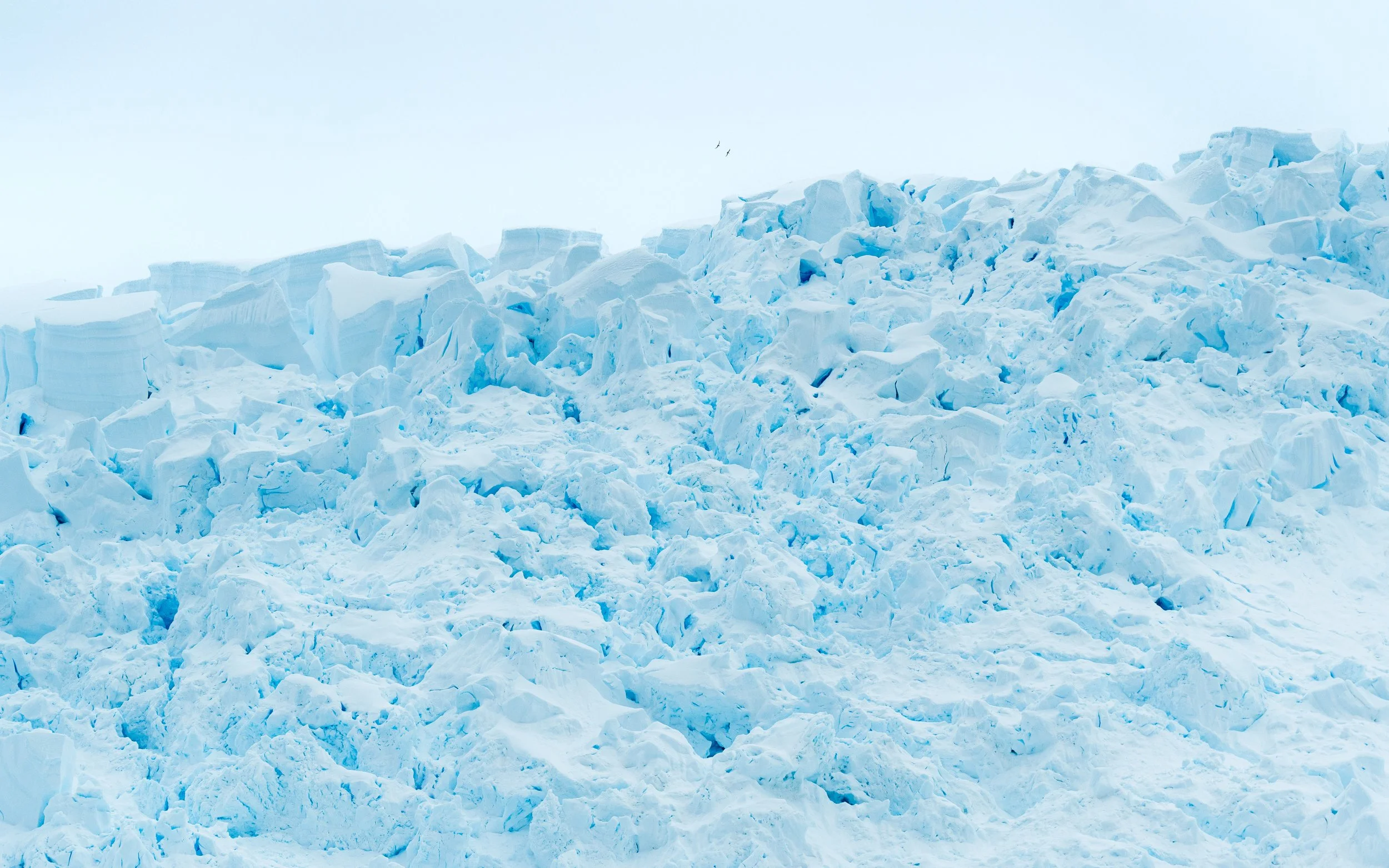 A landscape of ice and snow, with large chunks and formations of ice covering the ground under a pale sky.