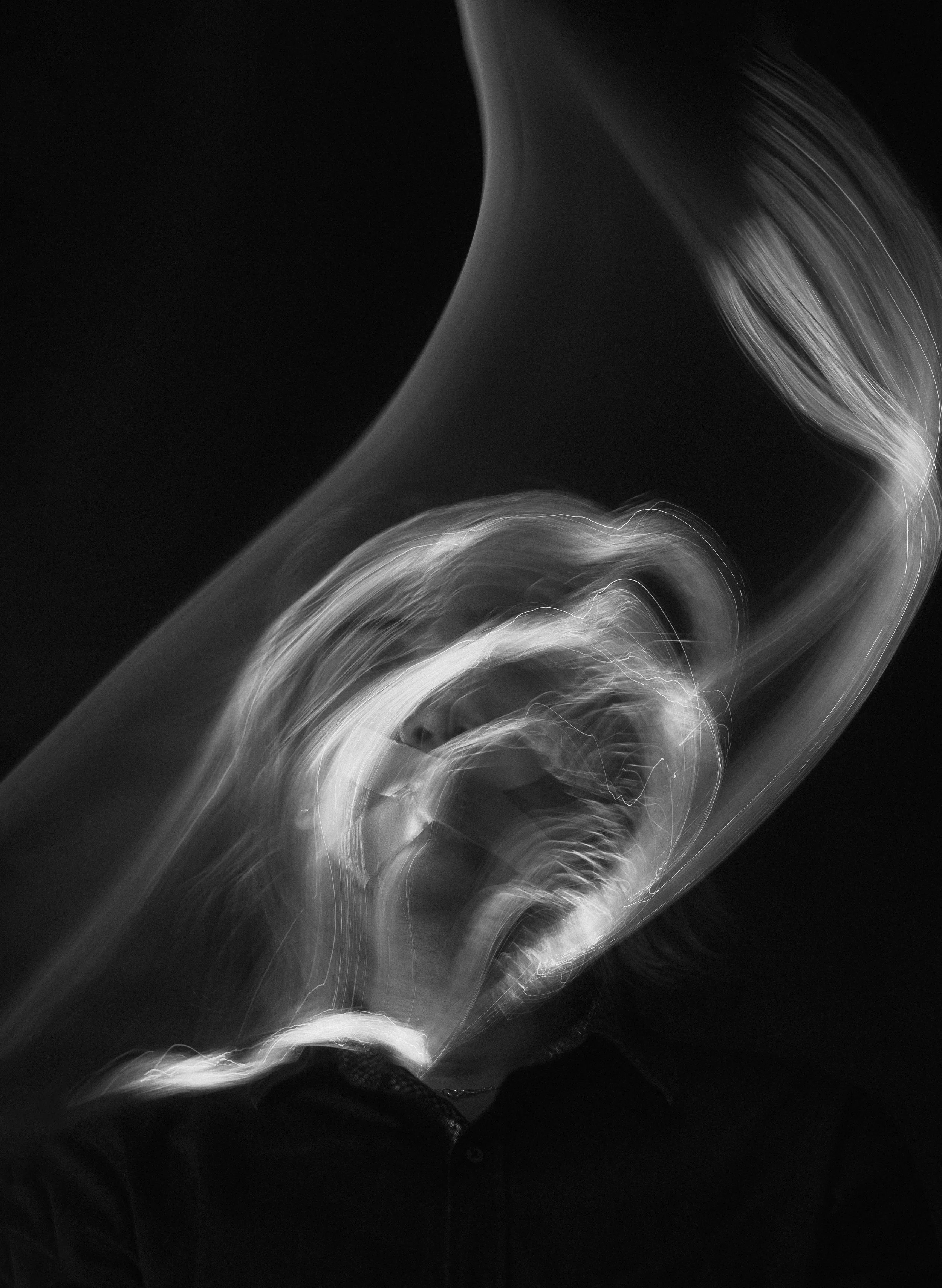 Black and white abstract photo featuring swirling light streaks and curved shapes.