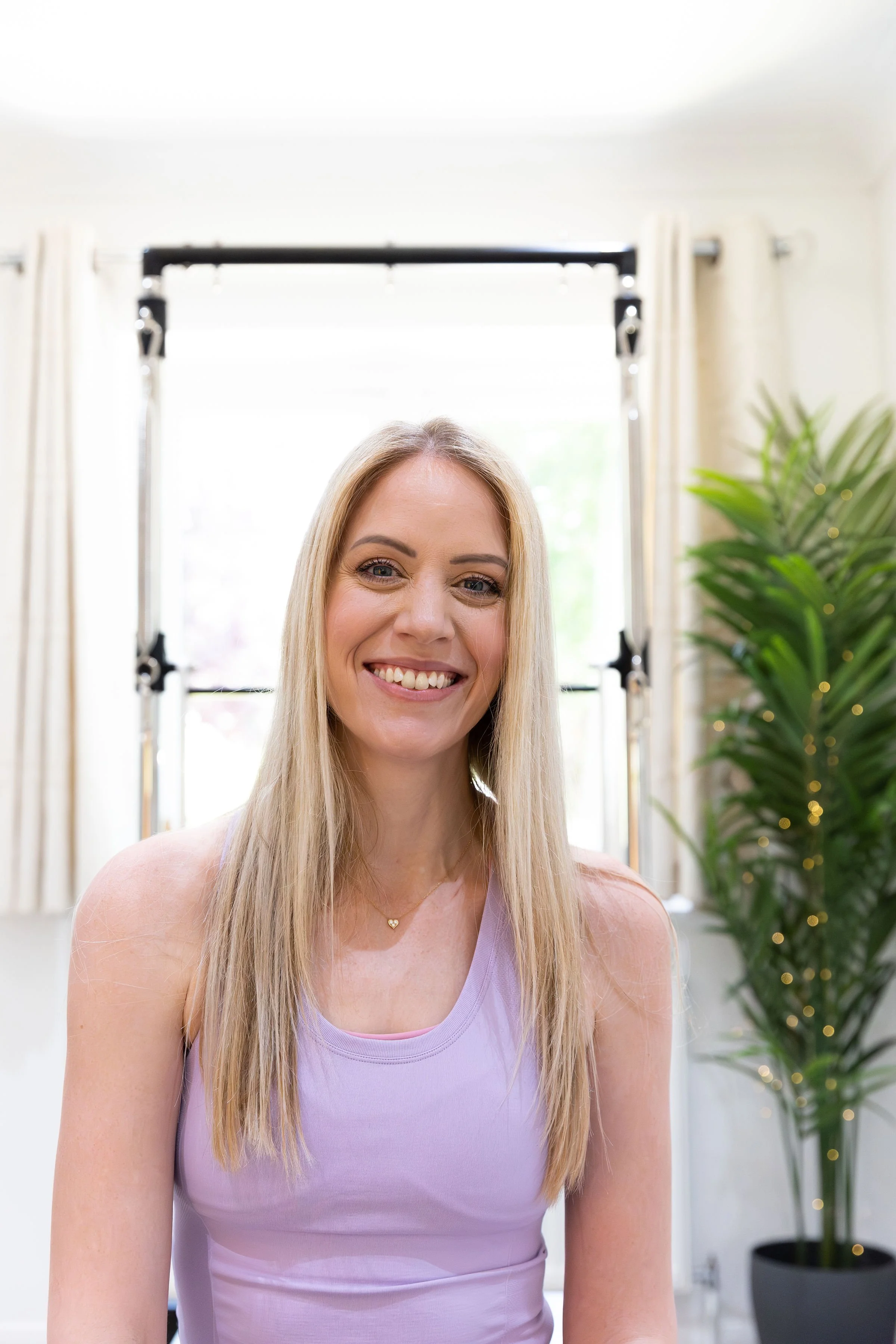 Meet Clare, founder of Flow & Glow Pilates in Ringwood, Hampshire, standing in the reformer studio. Passionate about helping people feel stronger, more confident, and at ease in their bodies through mindful movement.