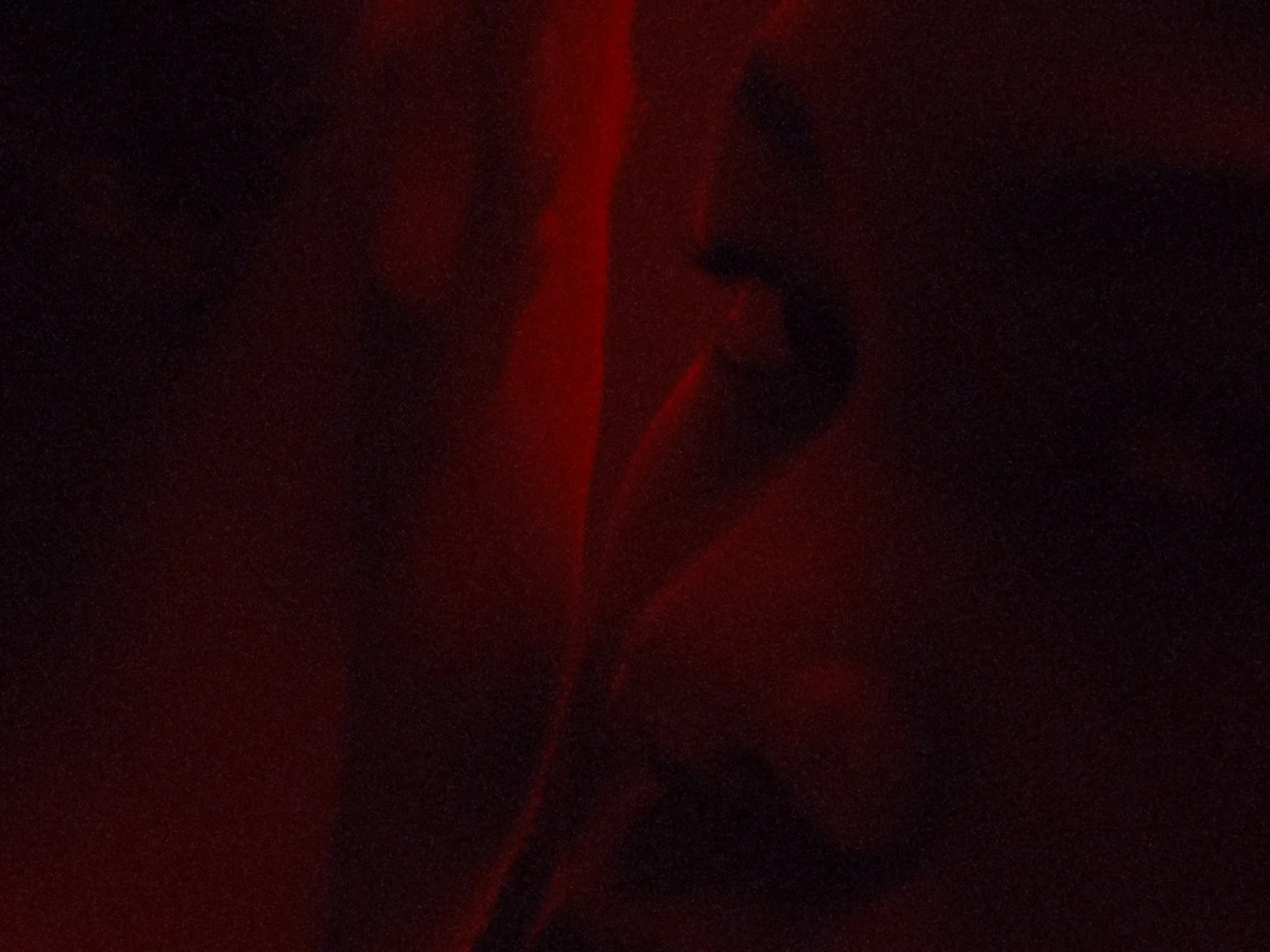 Dark image with faint red and black light, unclear subject.