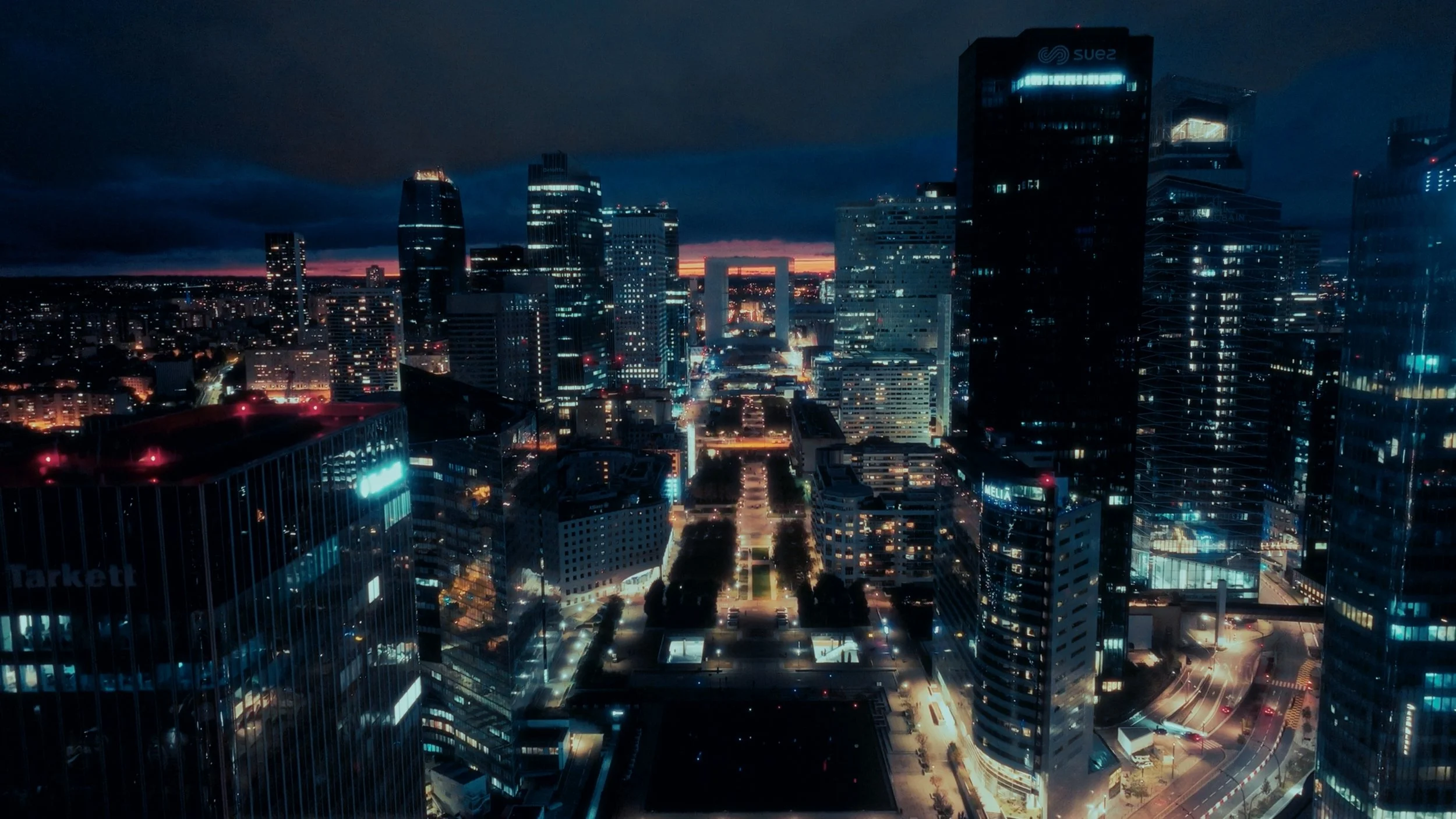 Nighttime aerial view of a city with skyscrapers and illuminated streets.
